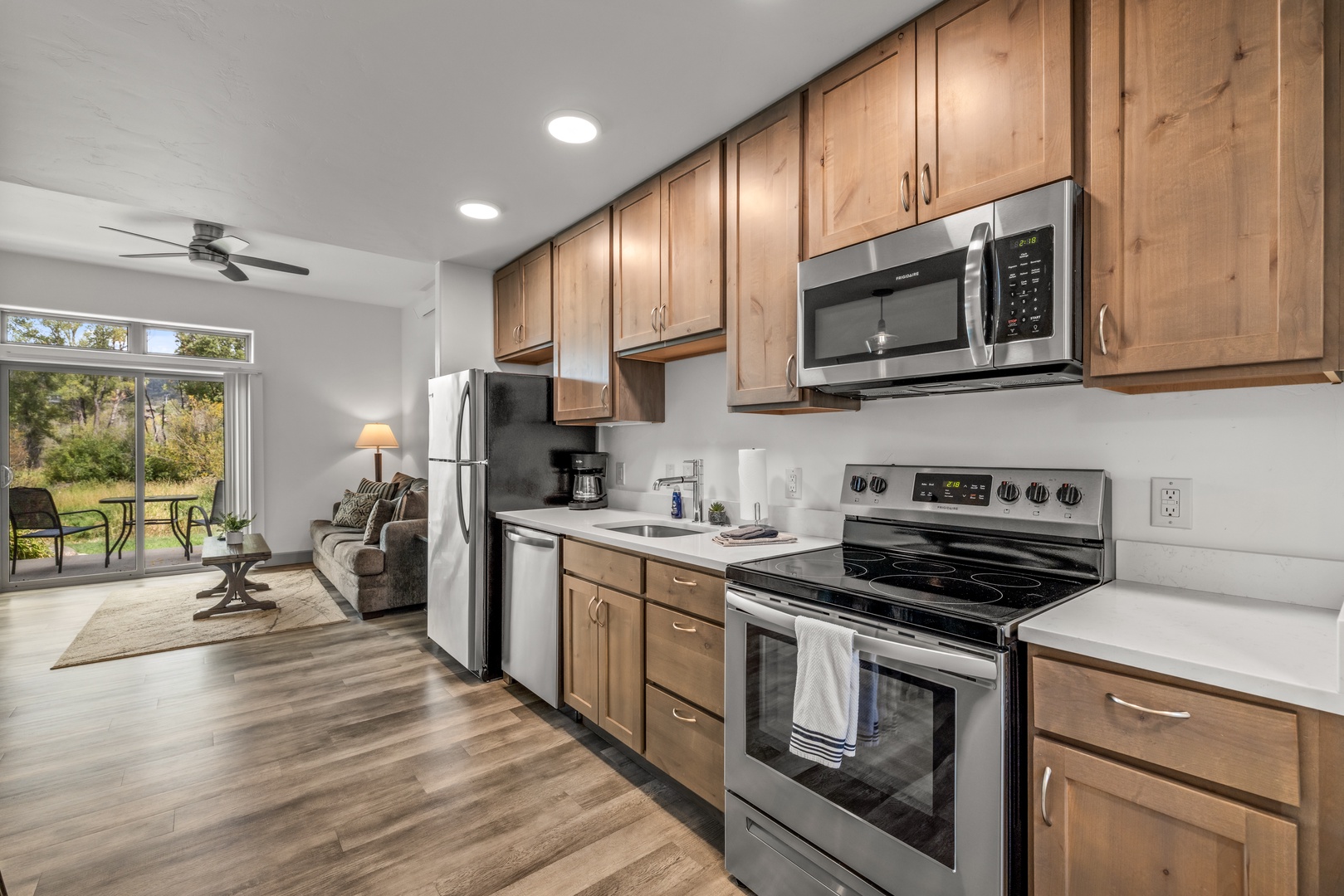Your fully equipped kitchen opens to a cozy living space and a peaceful green view through the patio door, offering the perfect blend of comfort and functionality.