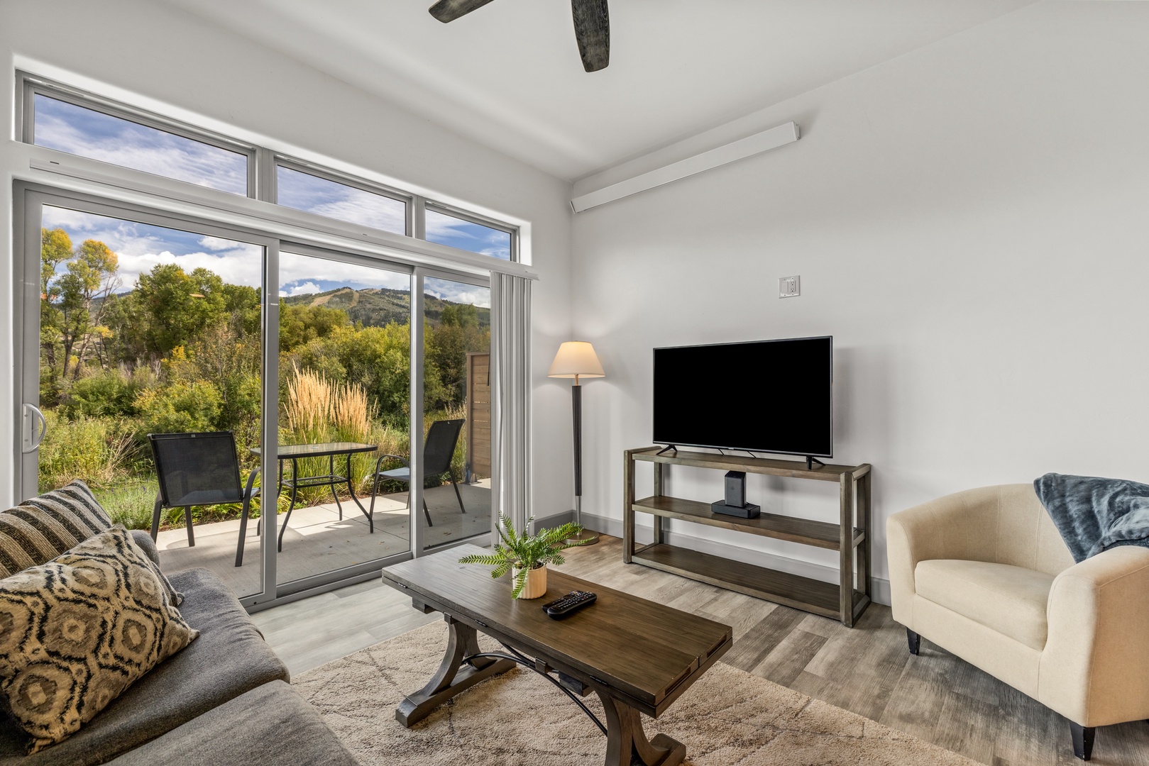 Your spacious living room opens onto a private patio with sweeping mountain and forest views. Settle in with natural light streaming through floor-to-ceiling glass, and let the serene landscape become your daily backdrop.