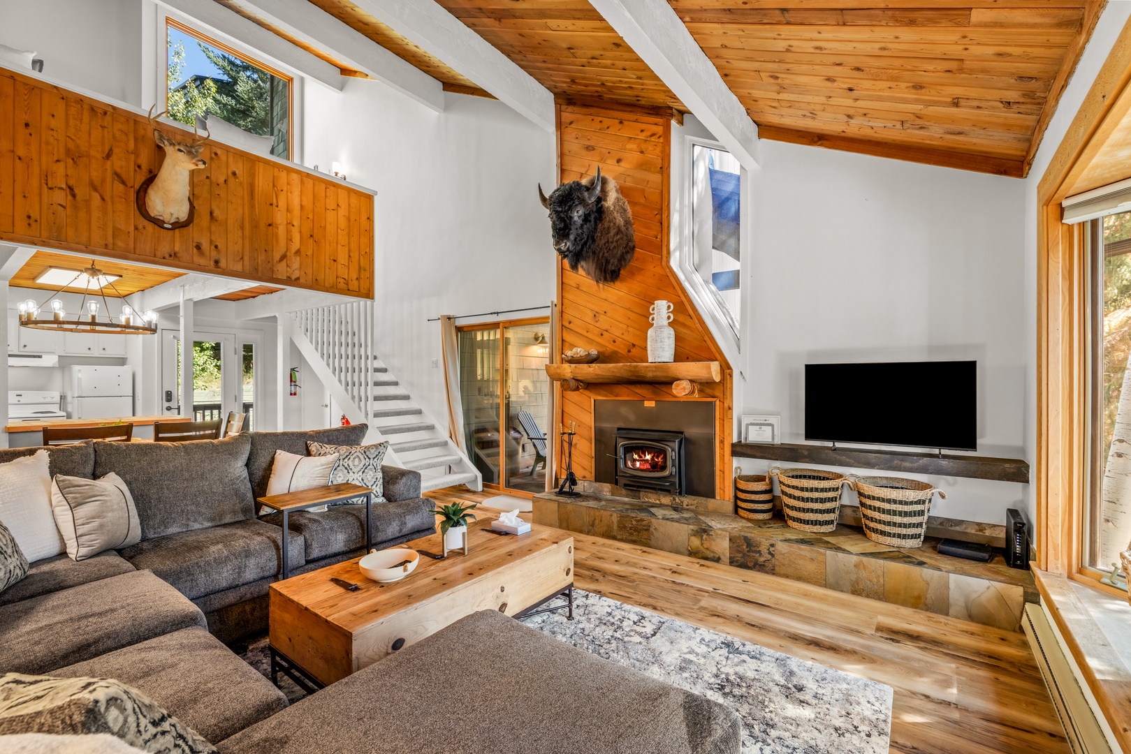 Unwind in your spacious living room, where vaulted wood-beam ceilings soar above plush seating and a cozy fireplace—perfect for gathering after mountain adventures.