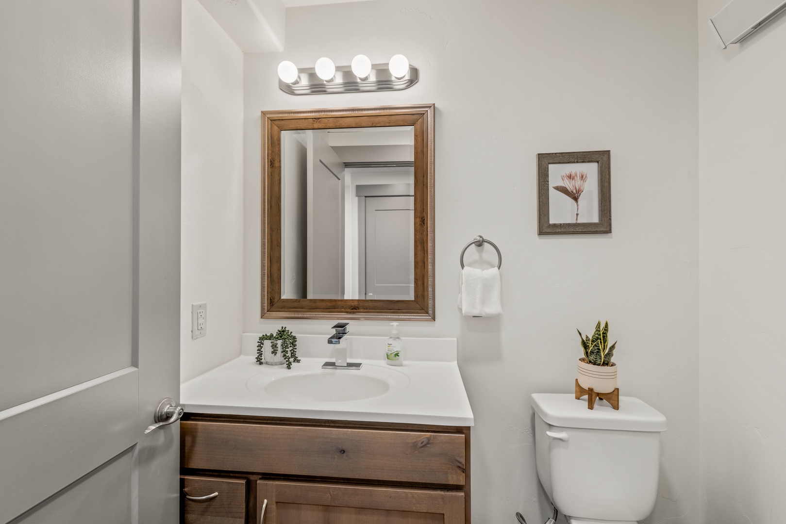 Step into your bright, thoughtfully designed bathroom where crisp white counters, warm wood accents, and soft vanity lighting create a serene space for your morning routine.