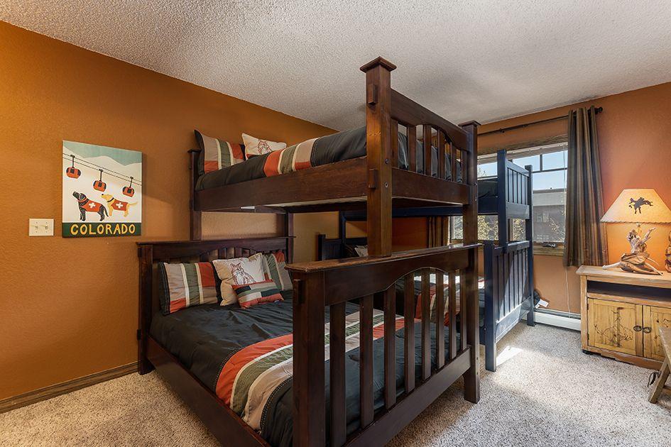 Your group will love this cozy bunk room, where warm wood tones and cheerful mountain-inspired decor create a welcoming retreat after a day of adventure.