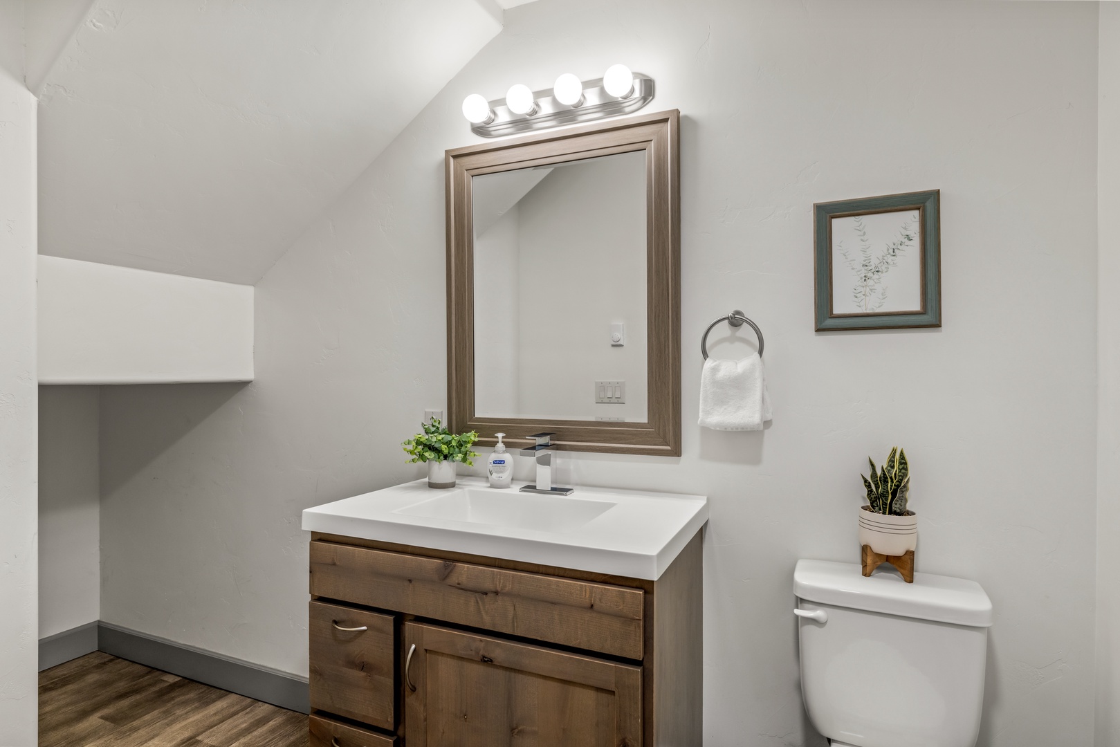 Step into your private bathroom featuring a modern vanity, elegant lighting, and thoughtful touches like fresh greenery. The crisp white counters and warm wood tones create a serene space where you can refresh and unwind.