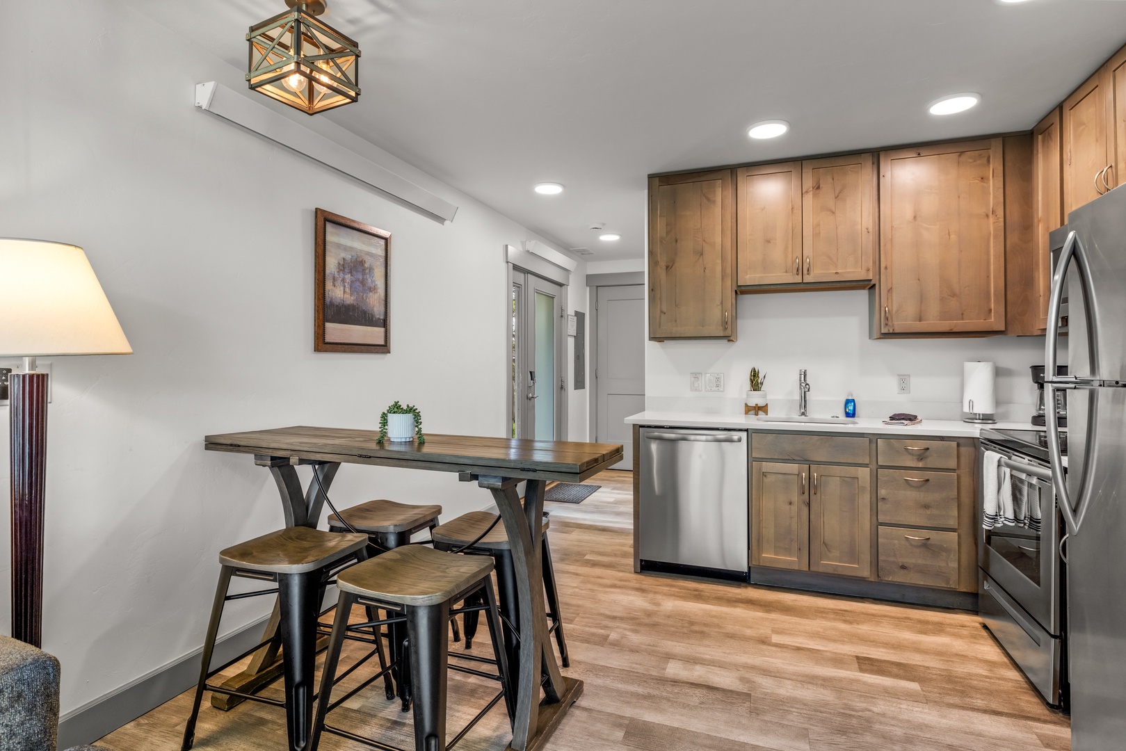 This stylish kitchen-dining space welcomes you with warm wood cabinetry, stainless steel appliances, and a cozy high-top table for meals and conversation, all bathed in bright, natural light.