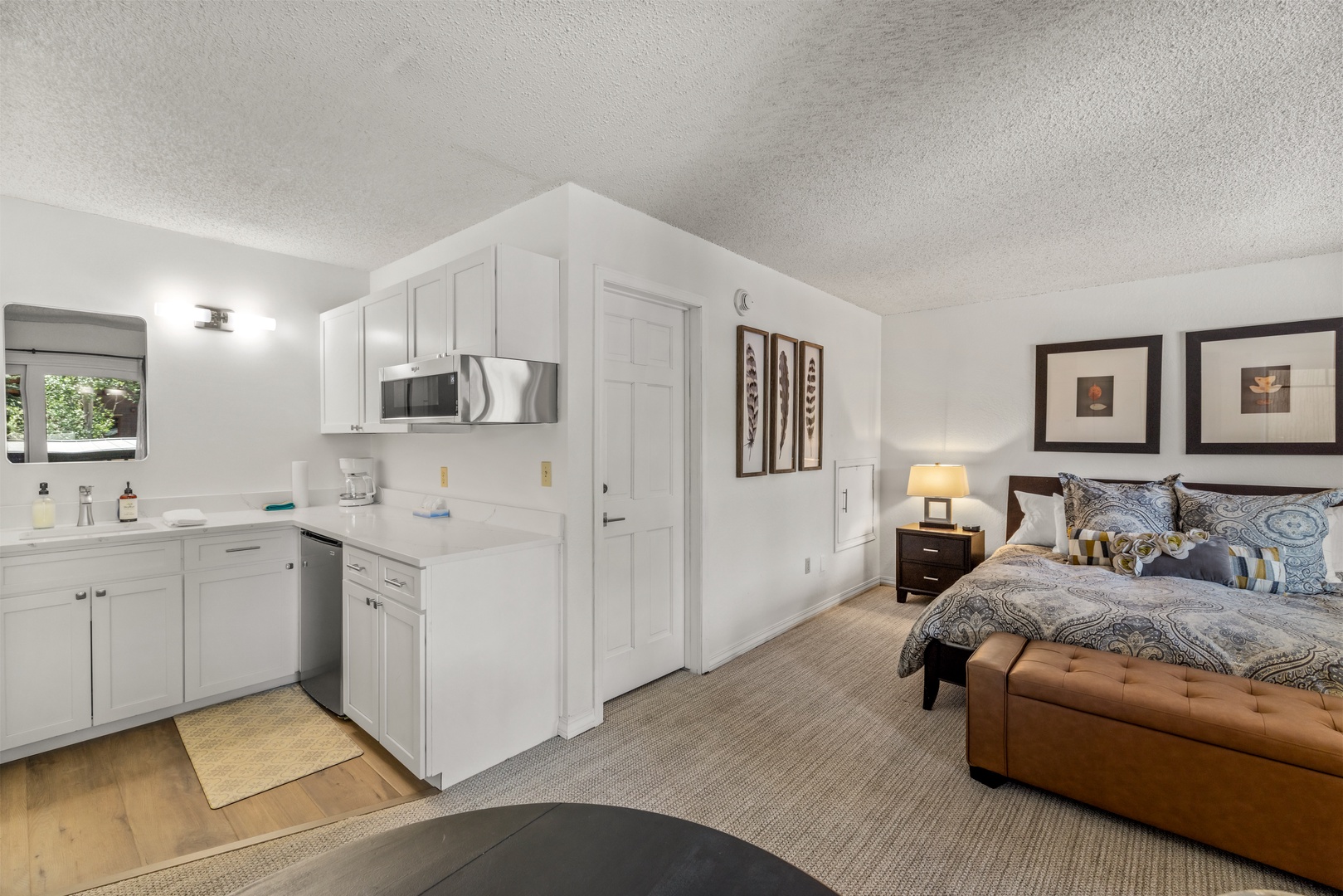 Your comfortable studio blends sleep and kitchen spaces seamlessly. Crisp white cabinetry and stainless appliances complement the cozy sleeping area, while natural light from the window brightens your entire retreat.