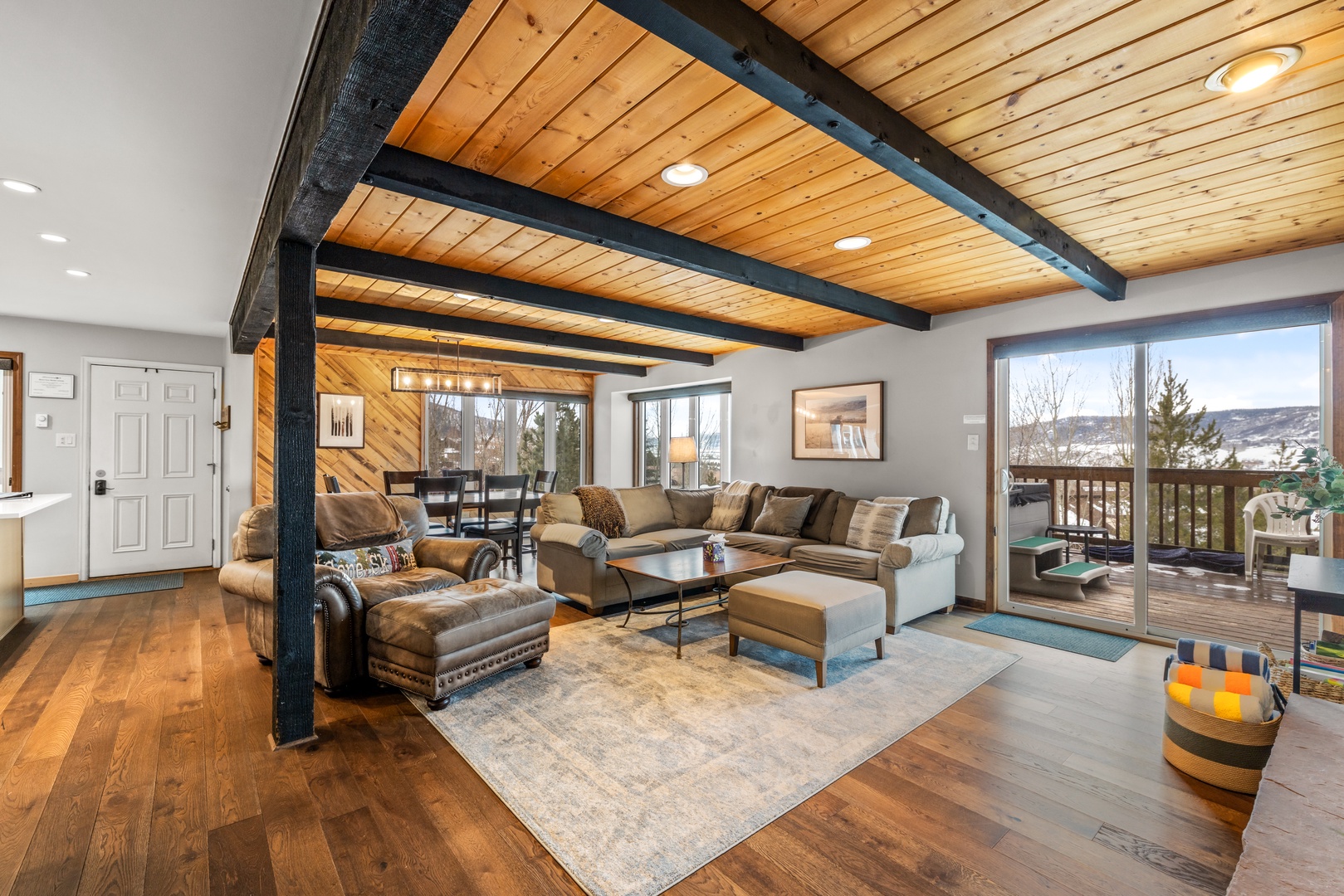 Relax under stunning exposed beams in this spacious living room, where plush seating and warm wood tones create your perfect mountain retreat.
