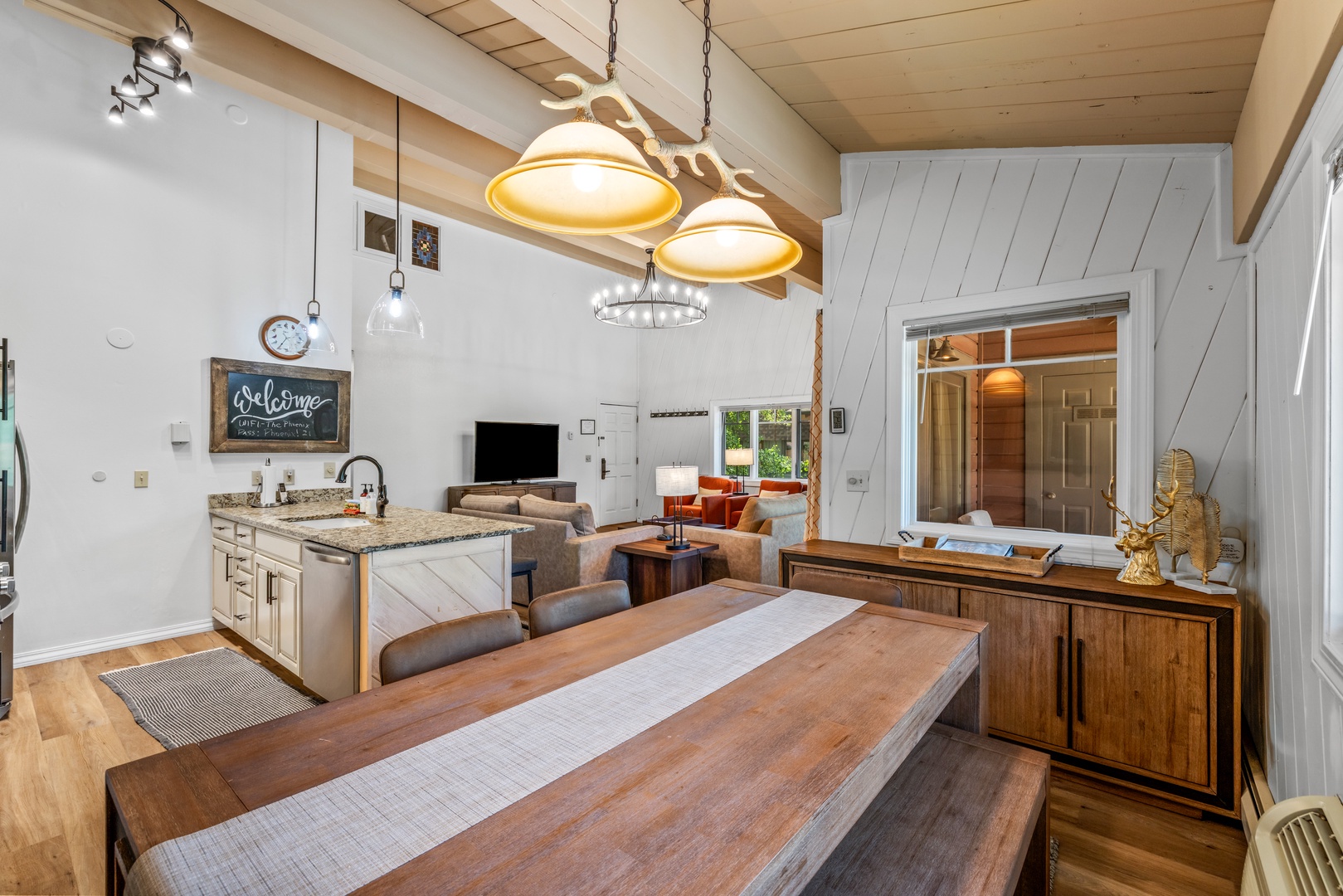 Gather around the rustic wooden dining table in this bright, open-concept space where your group can cook, dine, and relax together under vaulted ceilings and warm pendant lighting.