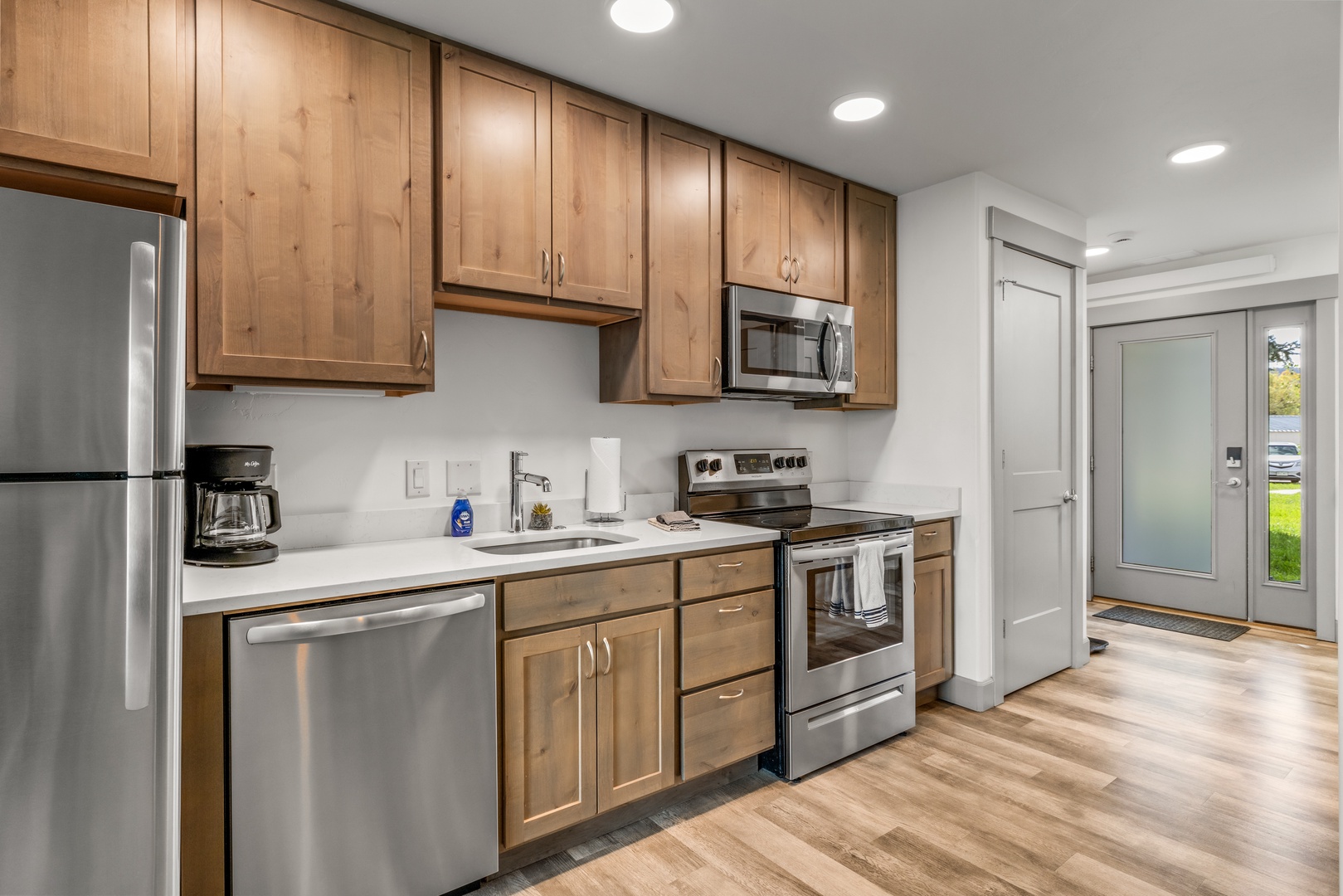 Step into your fully-equipped kitchen featuring warm wood cabinetry and modern stainless steel appliances. Bright, recessed lighting and clean quartz countertops make meal prep a breeze.