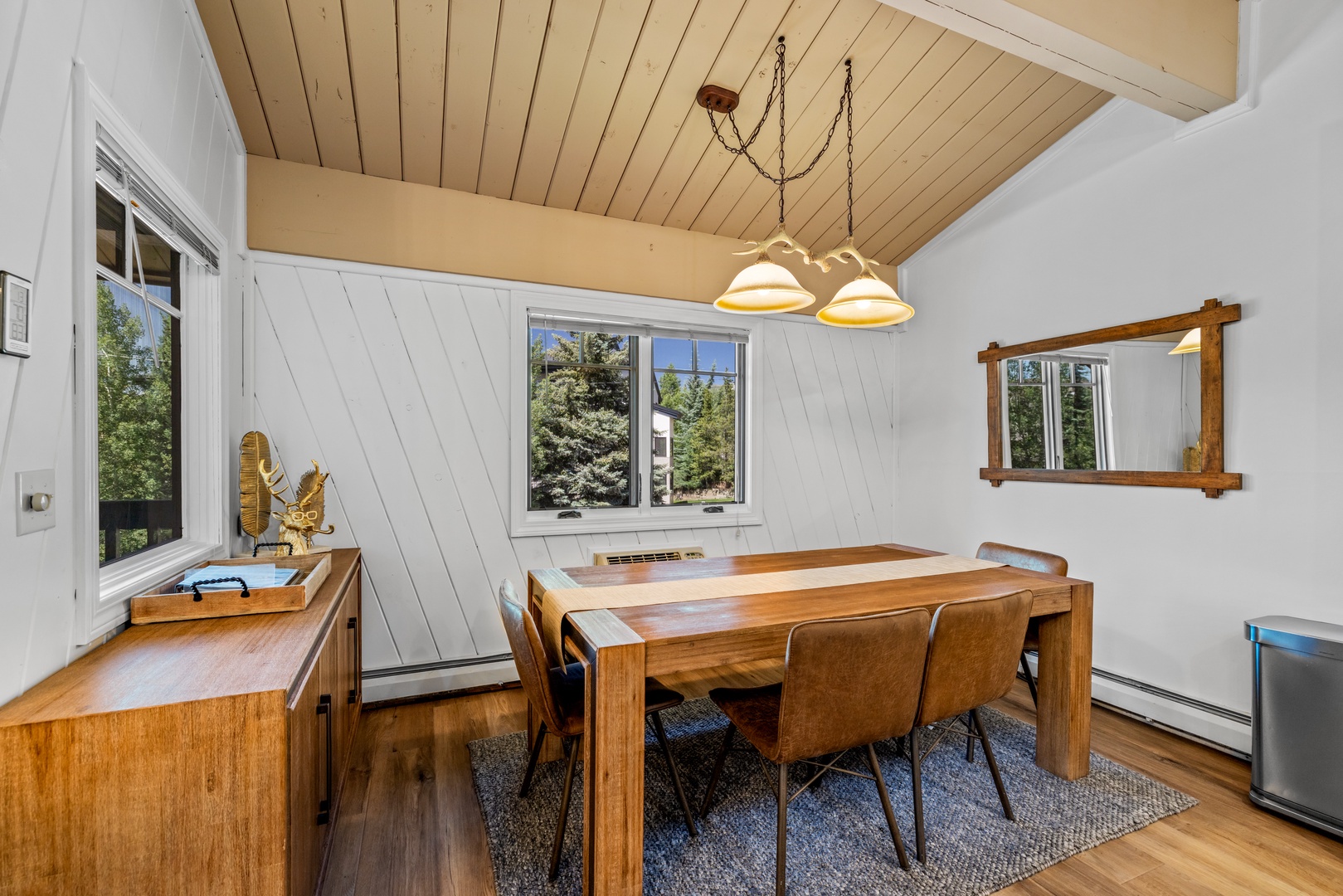 Gather around the handsome wooden table for meals and games, with natural light streaming through the windows and warm wood tones creating an inviting atmosphere for your group.