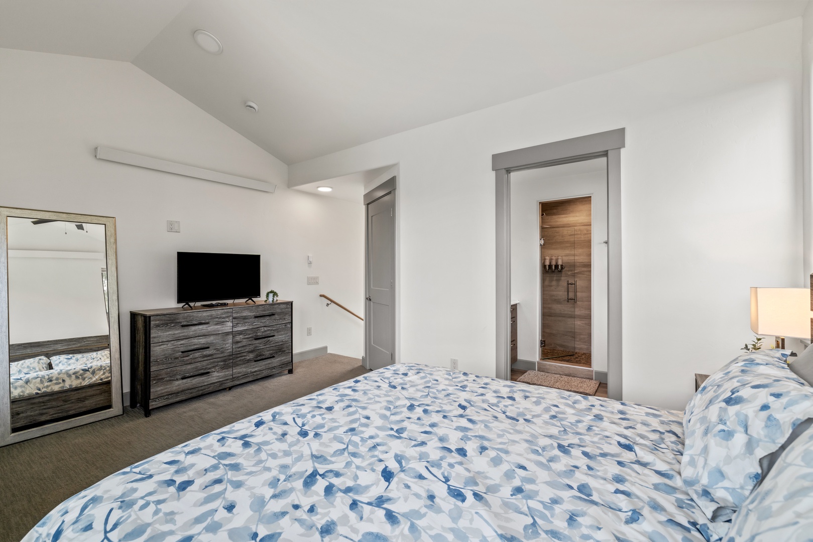 Unwind in your bright and modern bedroom featuring cozy bedding, a sleek entertainment setup, and your own private sauna just steps away.