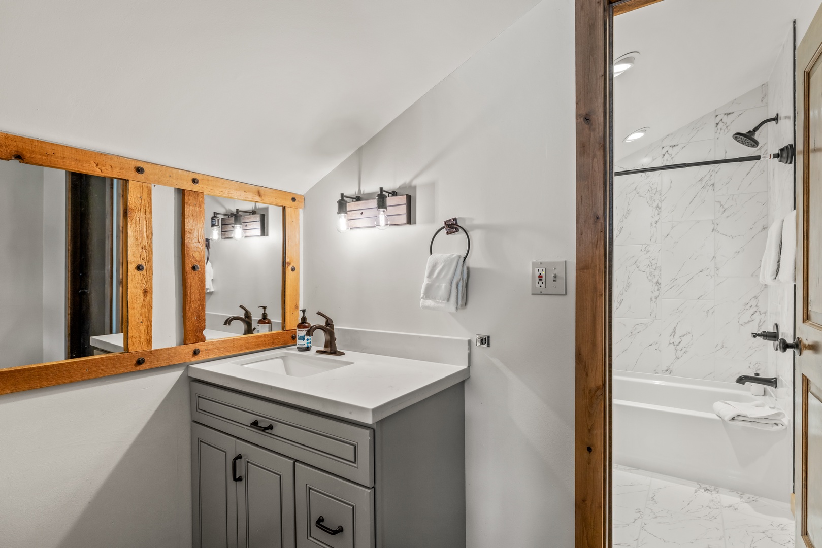 Step into your beautifully appointed bathroom featuring rustic wood accents, modern gray vanity, and elegant marble shower for your ultimate comfort.