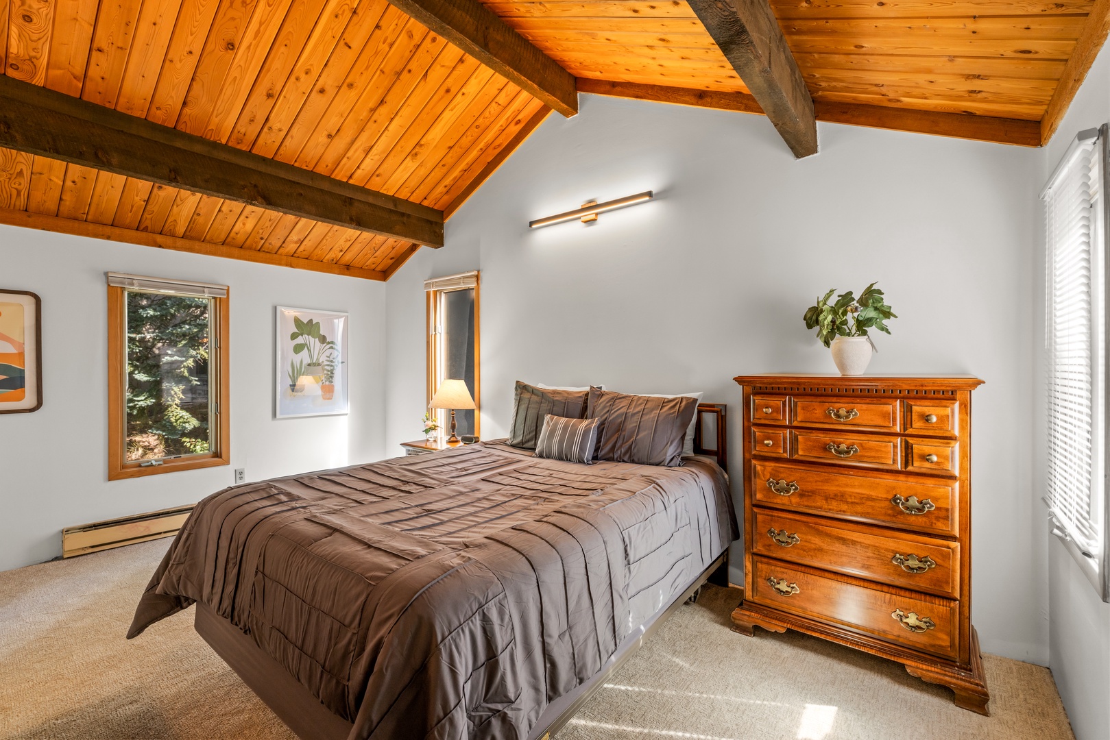 Sink into the plush bed beneath vaulted wood ceilings, where natural light pours through the window and warm details invite you to truly unwind.