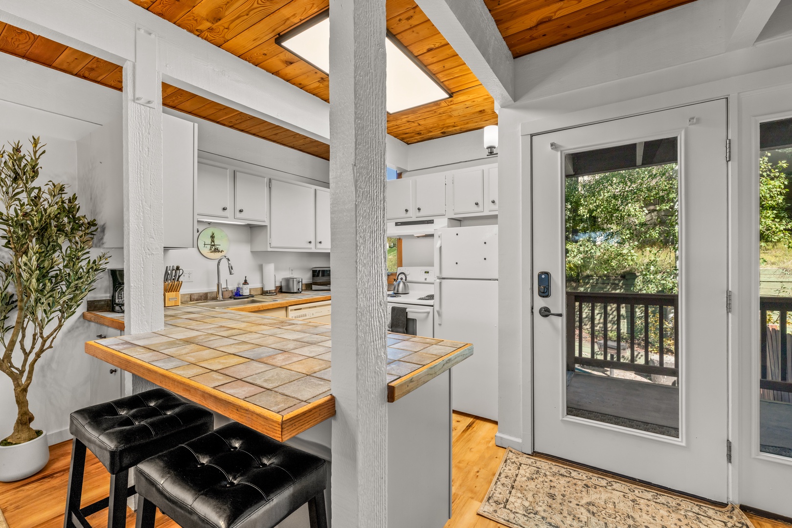 Step inside to discover warm wood ceilings that frame your open-concept kitchen and living space, where natural light pours through glass doors leading to your private balcony retreat.