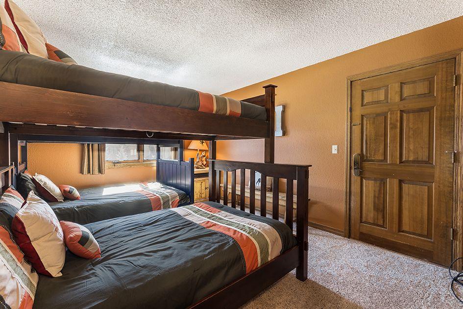 Your group will love this cozy bunk room, where rustic wood tones and warm colors create a welcoming retreat after mountain adventures.