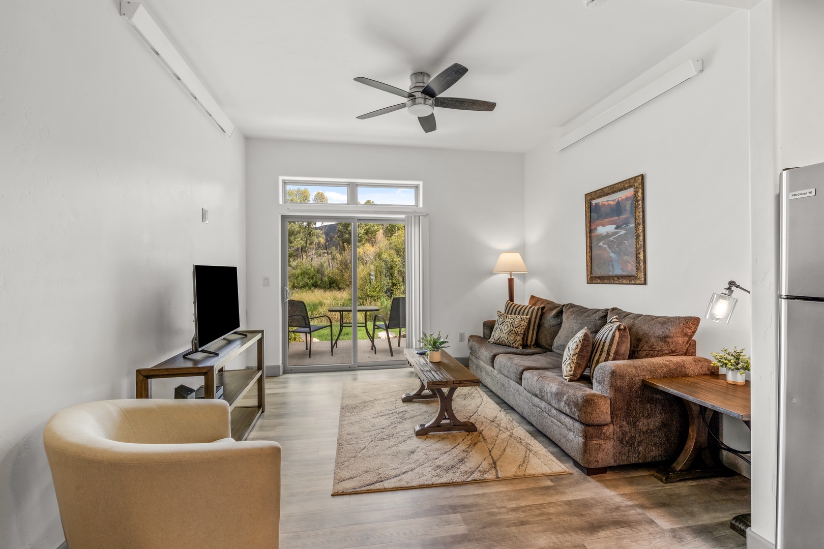 Bright, airy living space with vaulted ceilings and sliding doors opening to the outdoor patio. Natural light floods in, perfect for relaxing while overlooking the serene landscape.