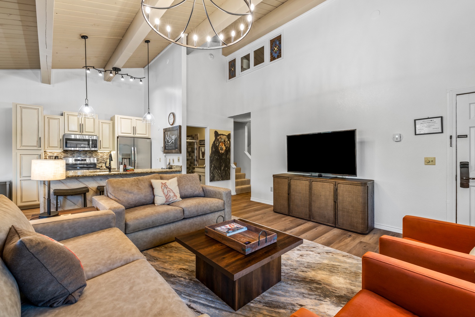 Open-concept living room with soaring vaulted ceilings and statement lighting. Perfect for relaxing on plush seating or gathering around the kitchen for meals and conversation.