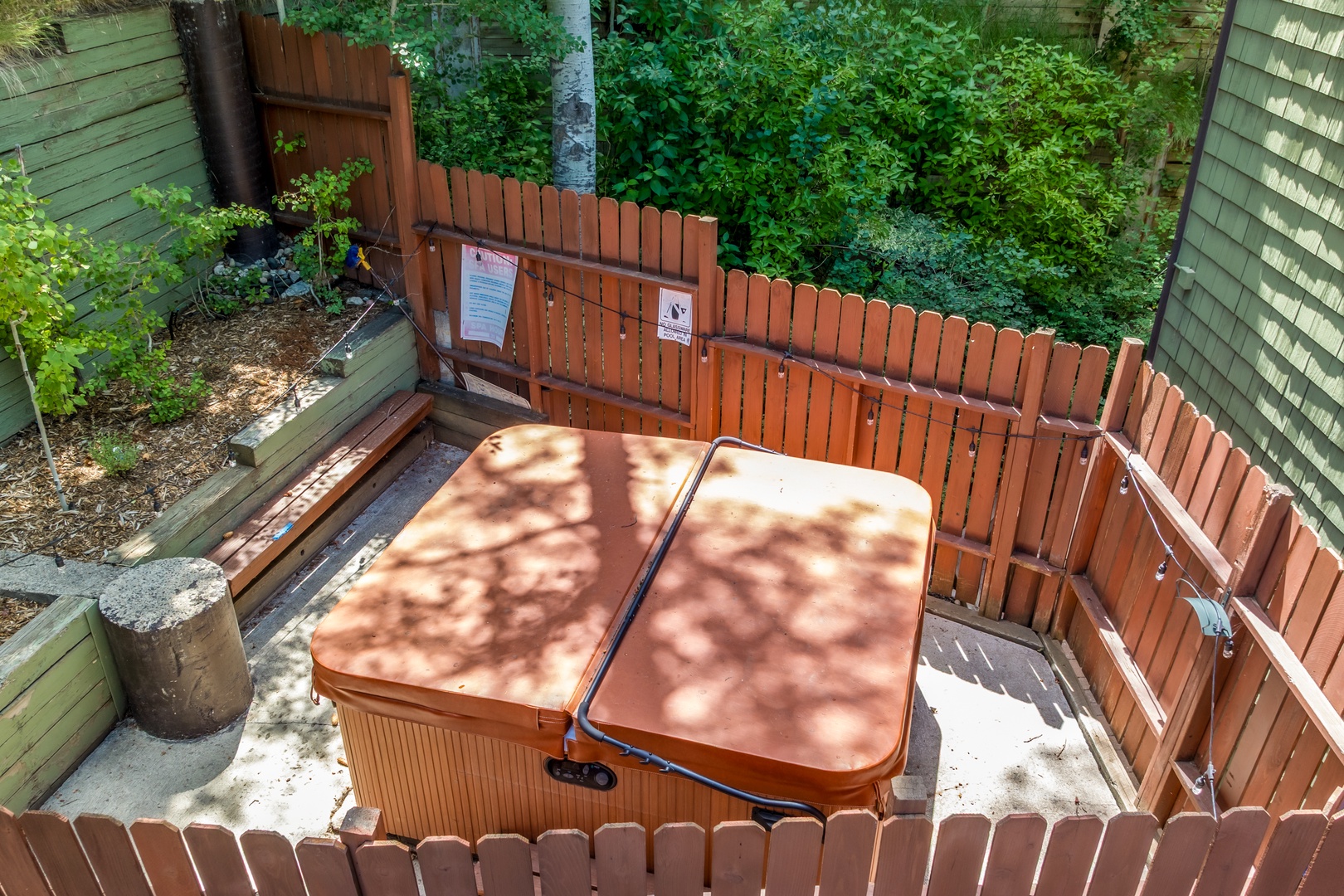 Slip into your private hot tub surrounded by tall trees and garden greenery, a perfect retreat for unwinding under dappled sunlight after exploring the area.