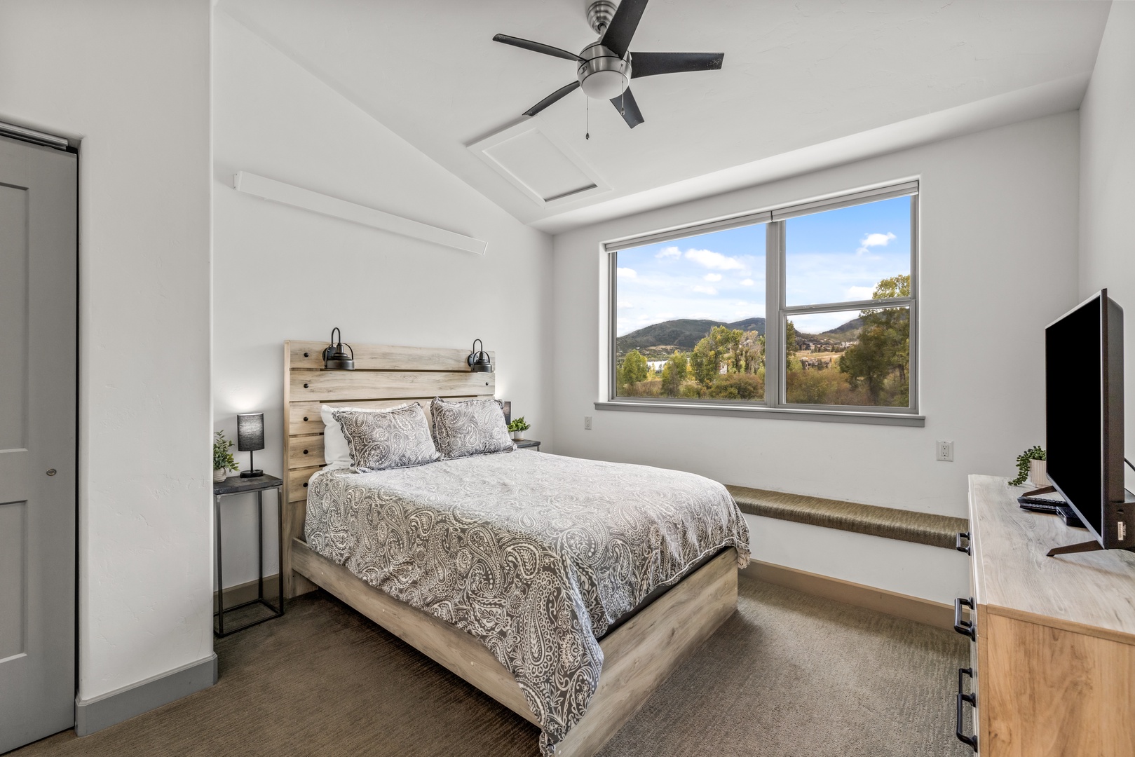 Wake up to sweeping mountain views through your window, where natural light fills this serene bedroom. Sink into plush bedding under a gentle ceiling fan, with every modern comfort thoughtfully arranged for your perfect retreat.