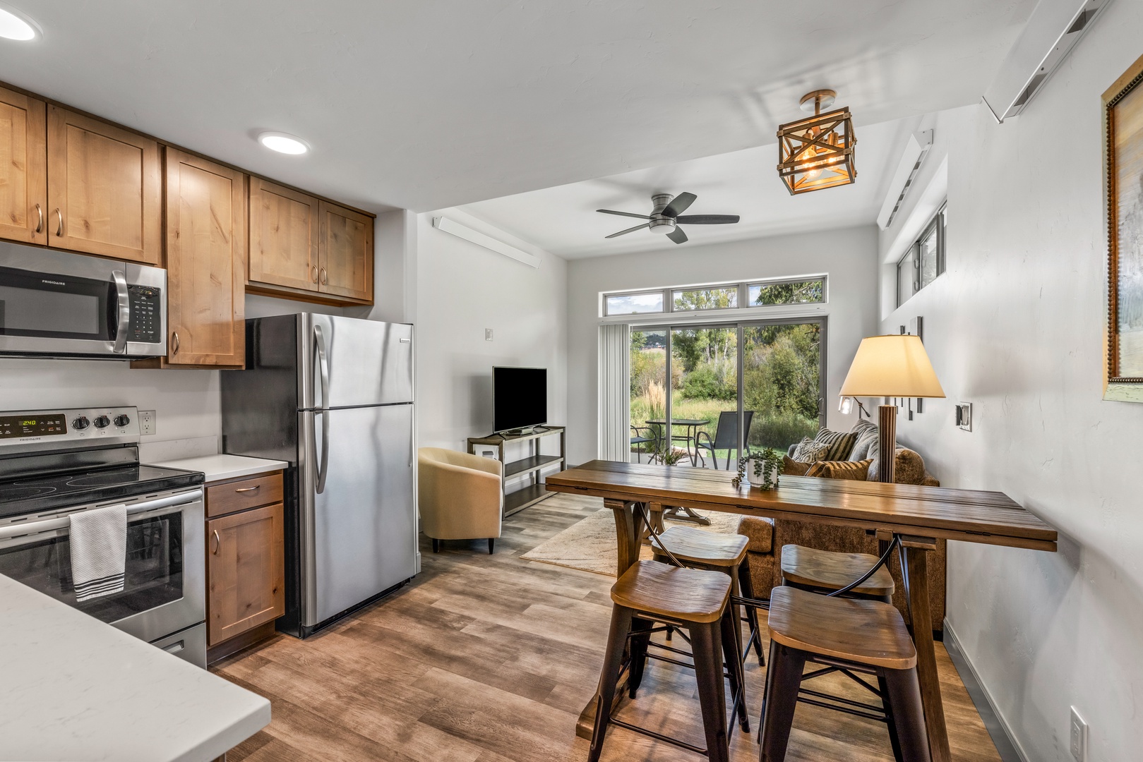 Step into your open-concept retreat where the kitchen flows seamlessly into the dining and living areas. Large glass doors frame the greenery outside, inviting natural light throughout your space.