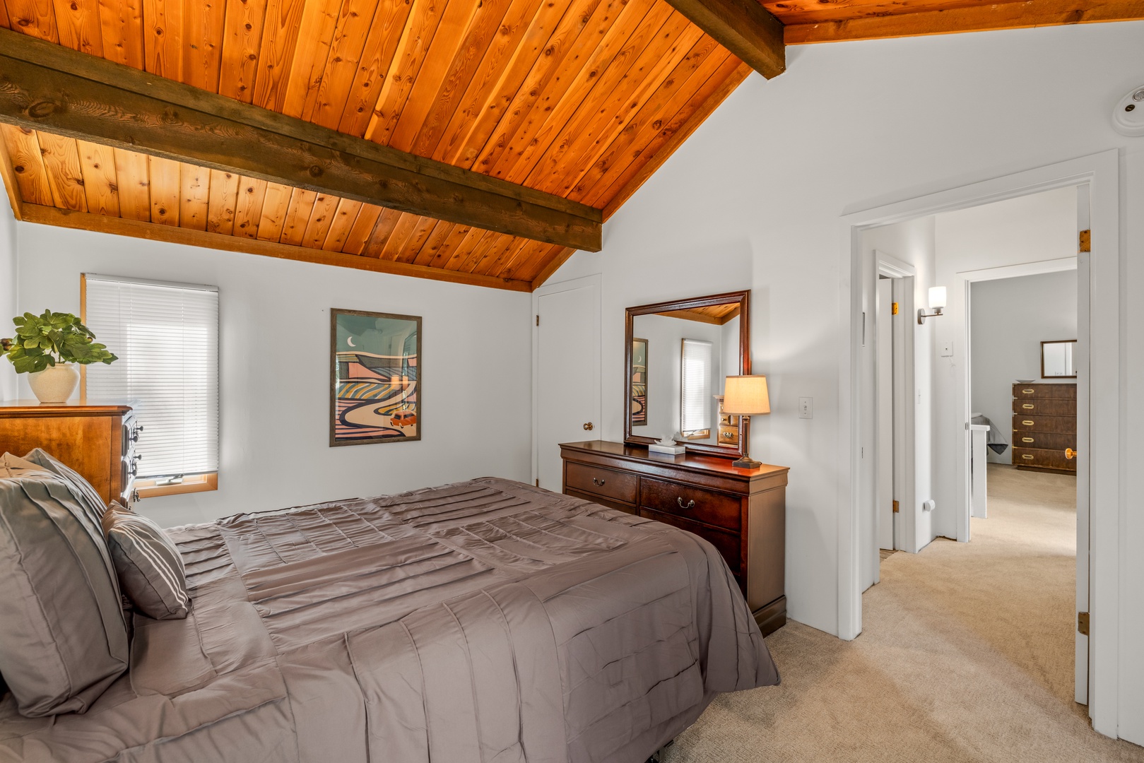 Drift off beneath soaring wood-beamed ceilings in your restful bedroom, where natural light and thoughtful touches create a cozy mountain retreat.