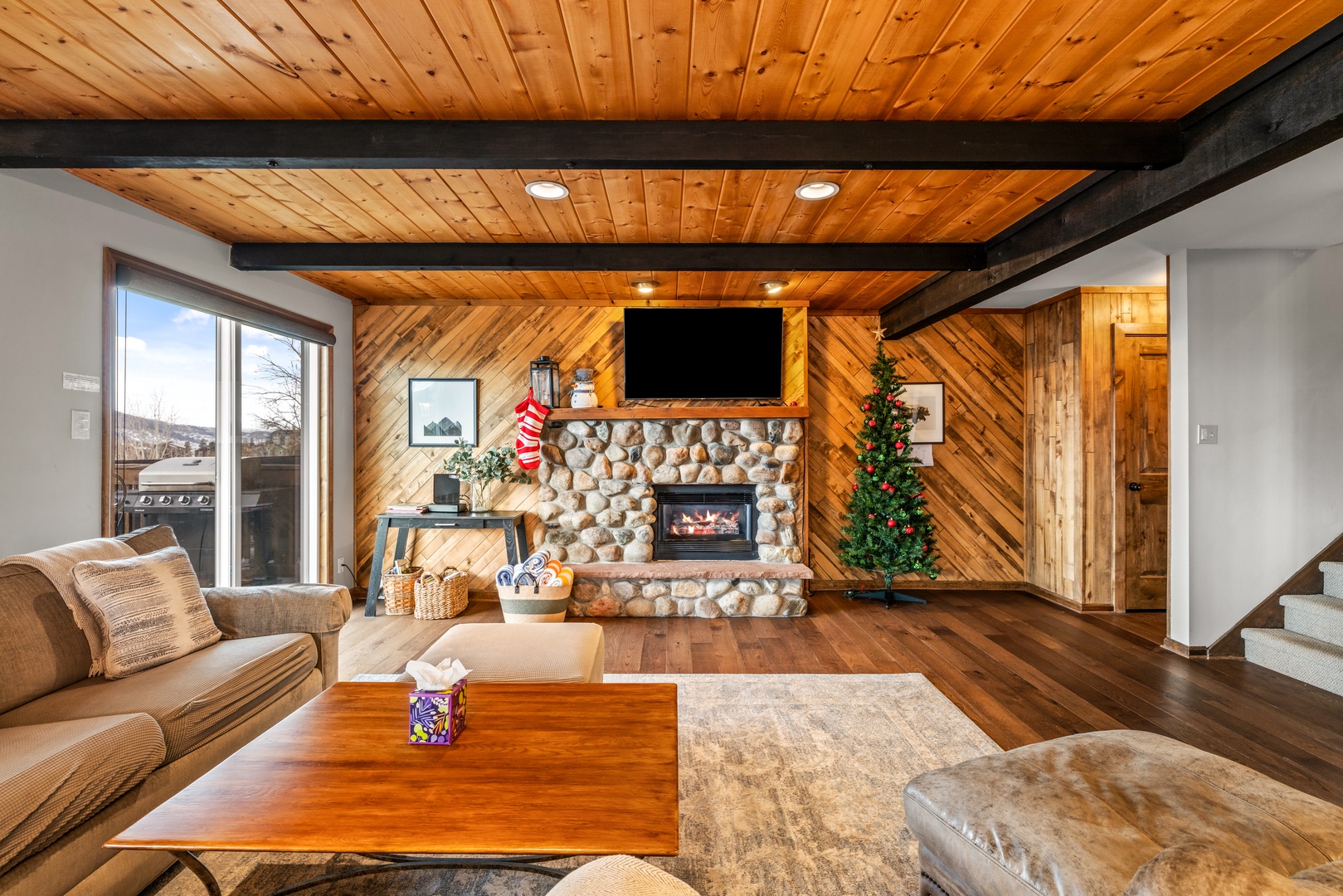 Cozy up in this inviting living room where warm wood beams frame your mountain getaway. The stone fireplace and plush seating create perfect moments for relaxation.