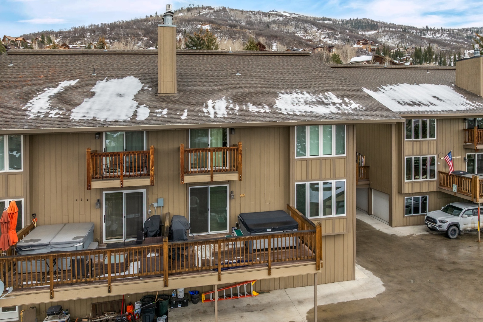 Multi-level townhouse complex nestled in a scenic mountain valley with snow-dusted peaks providing a stunning alpine backdrop.