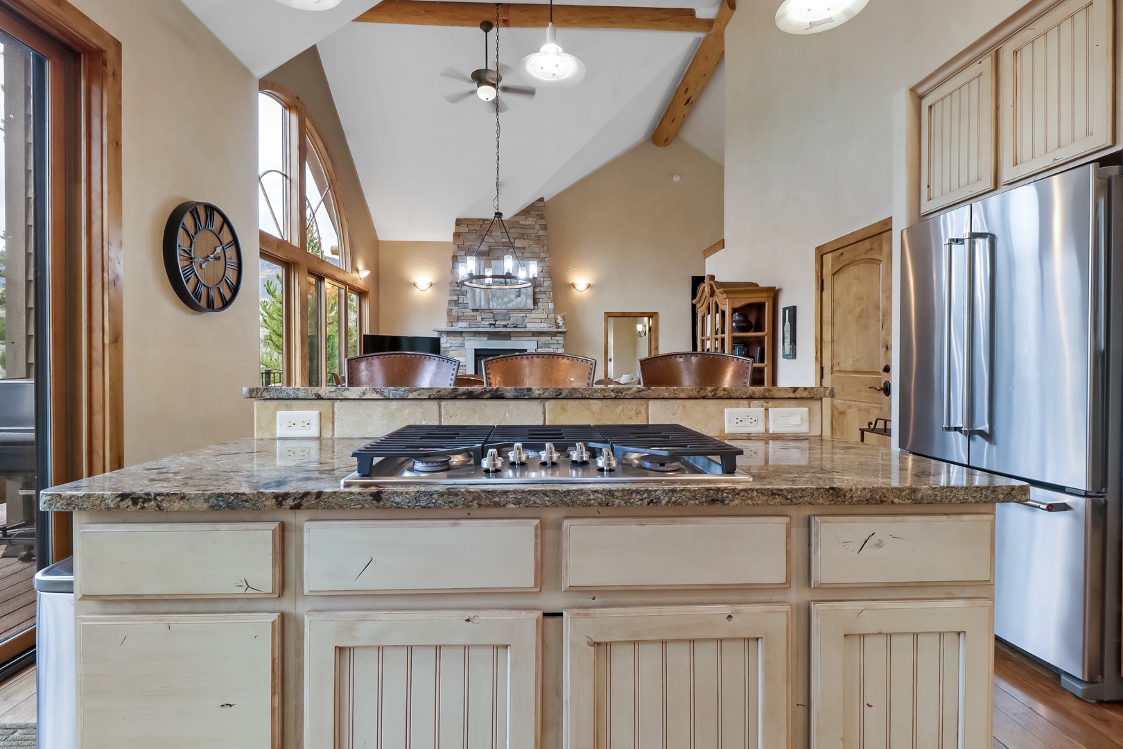 Your gourmet kitchen welcomes you with soaring vaulted ceilings, warm wood beams, and a stunning granite island with a professional gas cooktop—perfect for preparing delicious meals in style.
