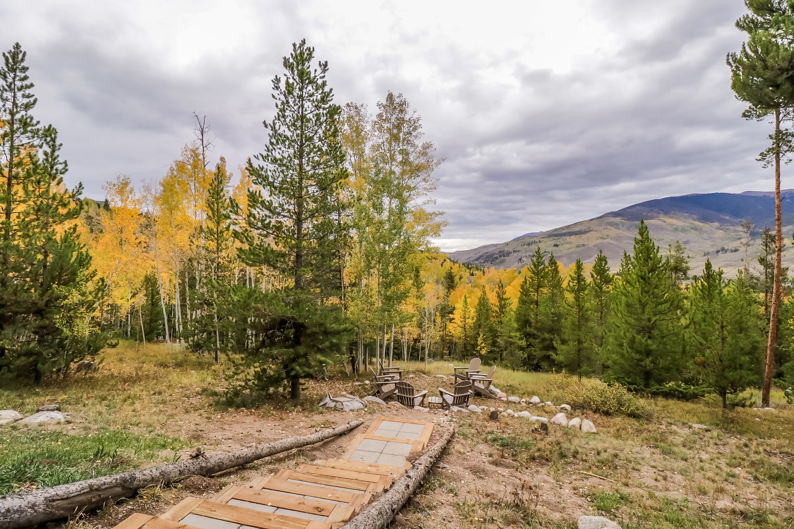 The property sits nestled among golden aspens and evergreens, with mountain views framing the peaceful outdoor seating area—a beautiful setting for a fall getaway.