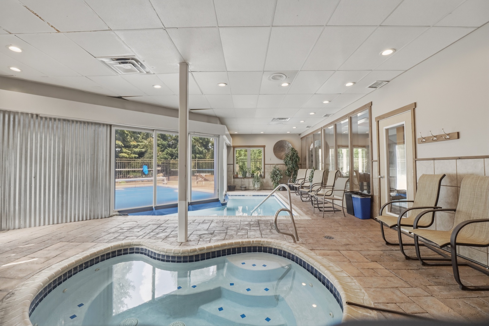 The indoor hot tub and pool area is a shared wellness space within the property, featuring loungers and access to outdoor areas—available for all guests to enjoy.