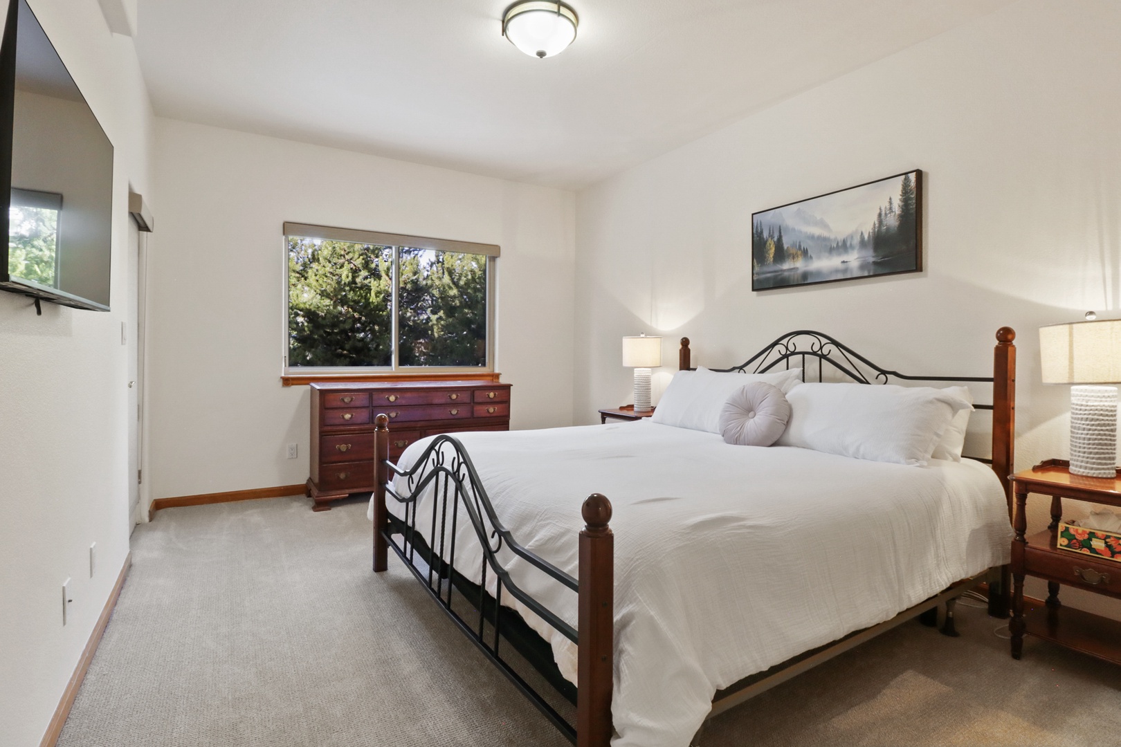 Sink into crisp white linens on this comfortable bed, where natural light streams through windows overlooking lush greenery for your perfect morning wake-up.