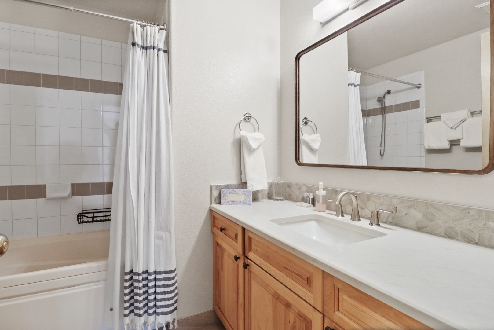 Your elegant bathroom features marble counters, warm wood cabinetry, and a relaxing tub-shower combo for unwinding after your adventures.