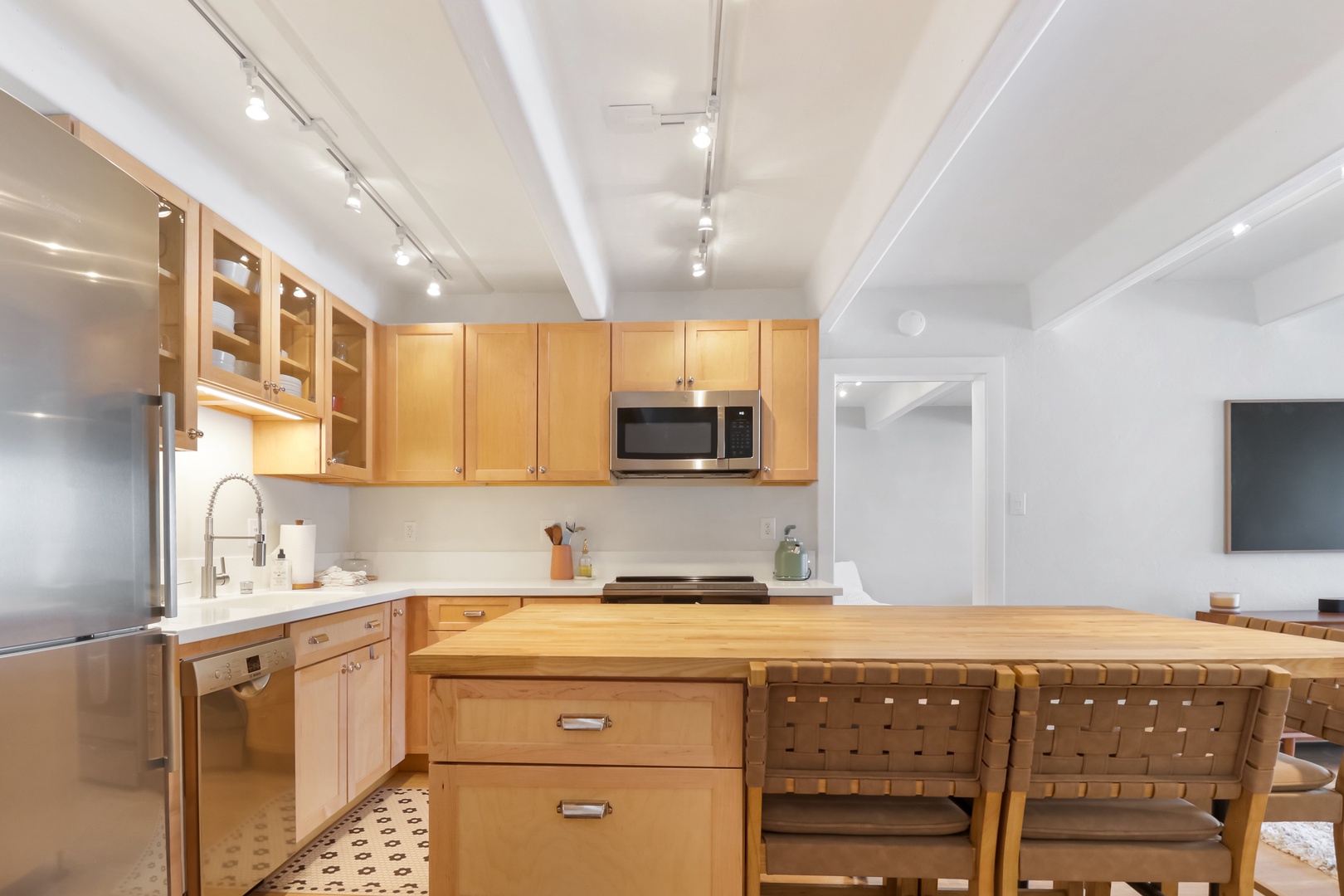 Cook in your bright, modern kitchen featuring warm wood cabinetry, sleek stainless appliances, and a spacious island perfect for casual dining.