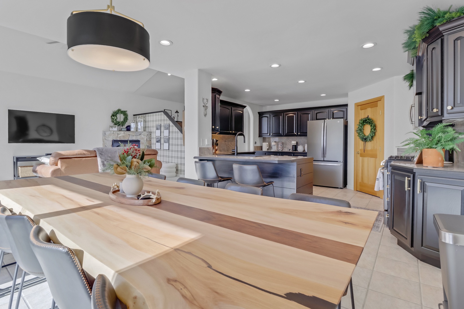 You'll love cooking and dining in this spacious open-plan kitchen with sleek dark cabinetry, modern appliances, and a gorgeous live-edge wood dining table perfect for memorable meals.