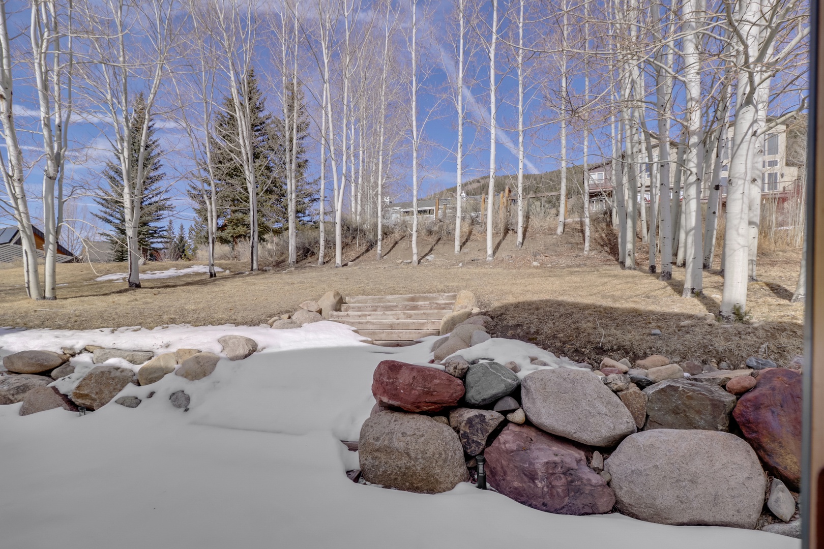 Beautiful winter landscape with snow-covered natural stone features and bare aspen trees under bright blue skies.