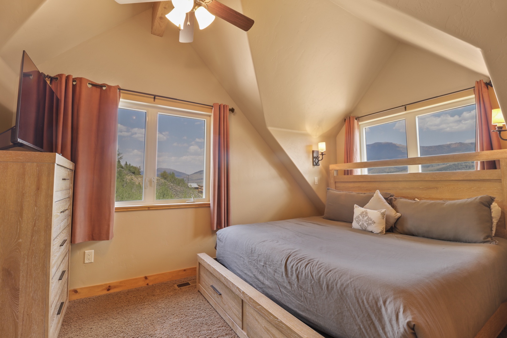 Wake up to stunning mountain vistas framed by your window. This cozy bedroom blends rustic wood accents with plush bedding, creating the perfect retreat after a day exploring the surrounding peaks.