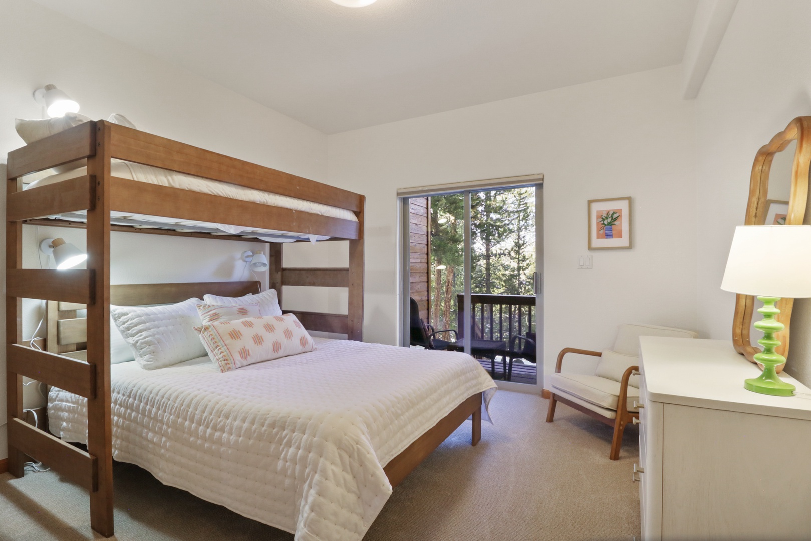 Drift off in this cozy bedroom featuring crisp white linens and a peaceful balcony view of leafy trees.