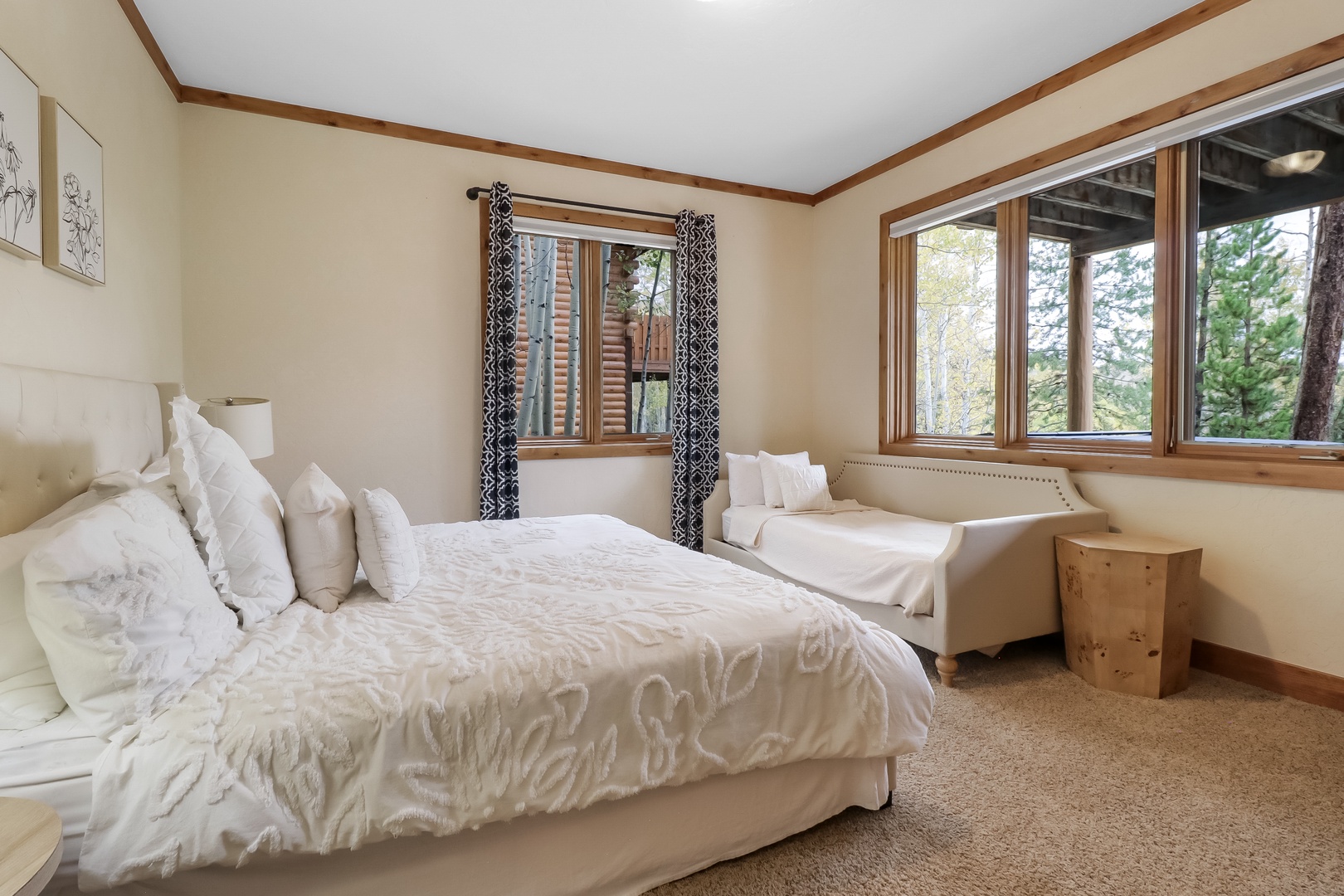 Sink into plush white linens and let sunlight stream through your windows, where treetops frame a peaceful natural setting. Your cozy retreat offers a serene escape surrounded by nature.