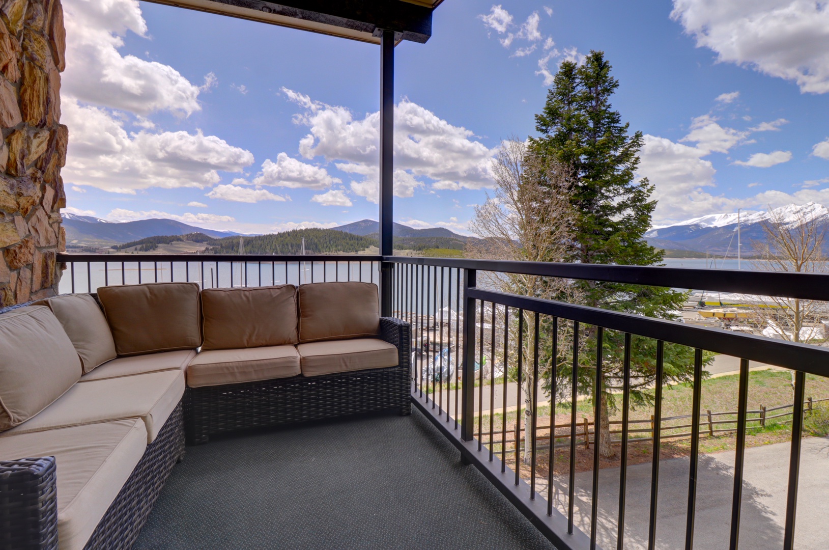Settle into your private covered balcony with plush seating and soak up sweeping mountain and water views—a perfect spot to unwind with morning coffee or evening relaxation.