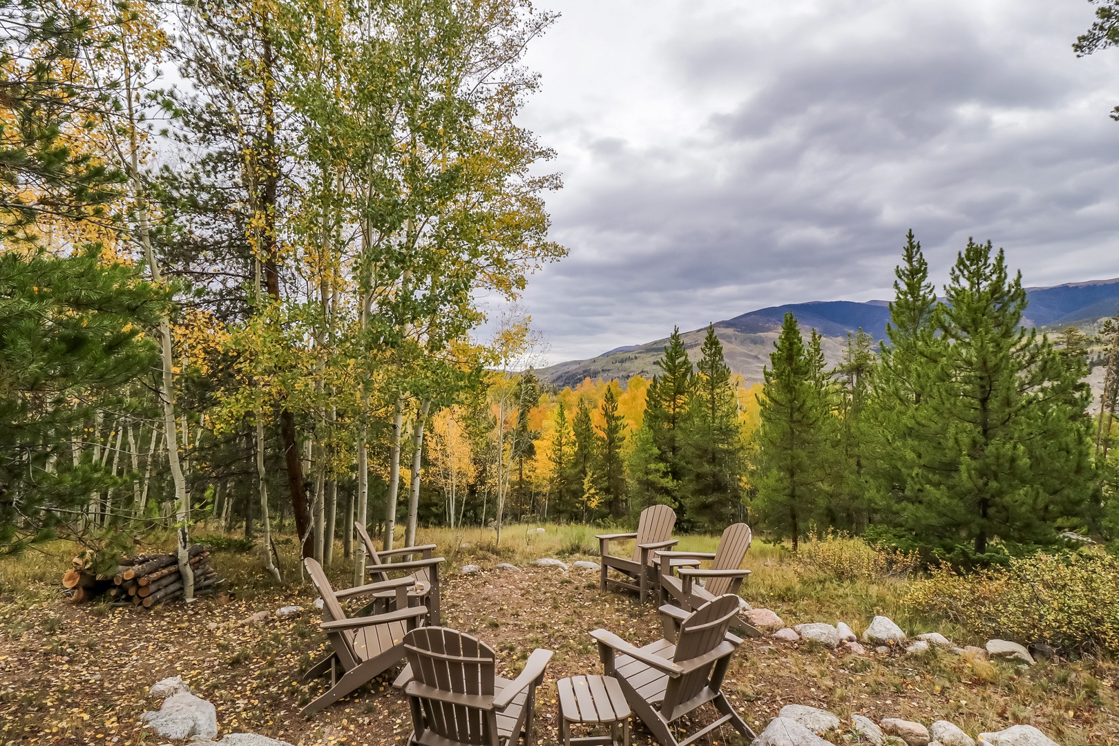 Outdoor seating area with Adirondack chairs set among aspens and pines, offering views of the surrounding mountains and autumn foliage.