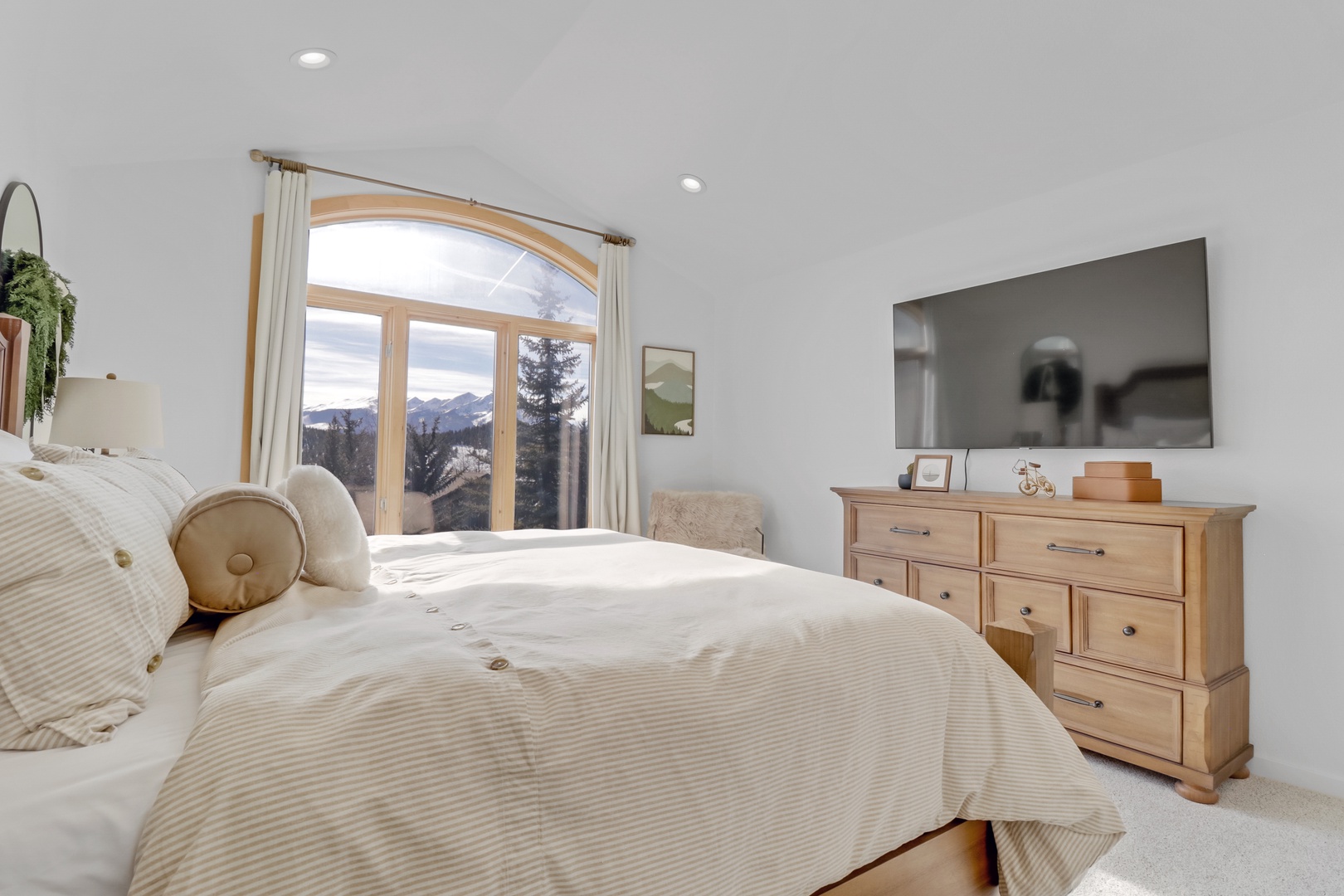 Wake up to breathtaking mountain views from your serene bedroom, where natural light floods through the arched window.
