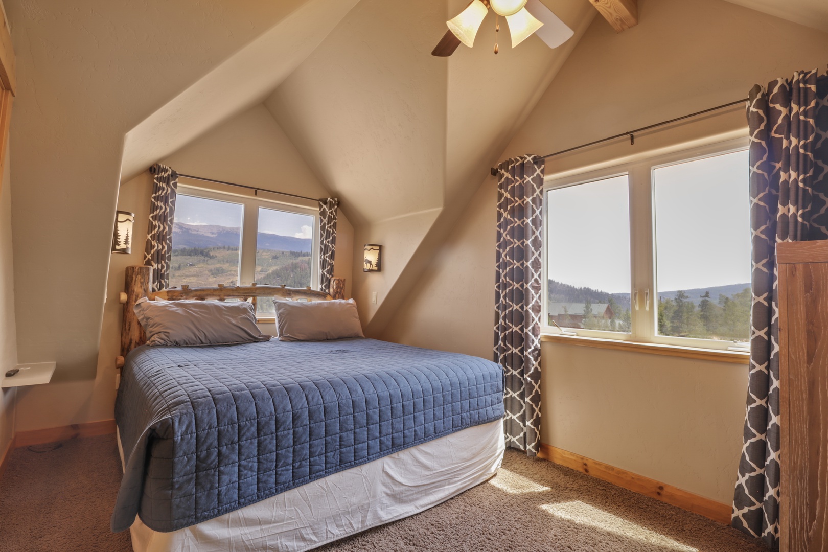 Wake up in your cozy bedroom retreat, where two windows frame stunning mountain vistas. The vaulted ceiling adds an airy feel, and natural light fills the space, inviting you to start your day surrounded by peaceful scenery.