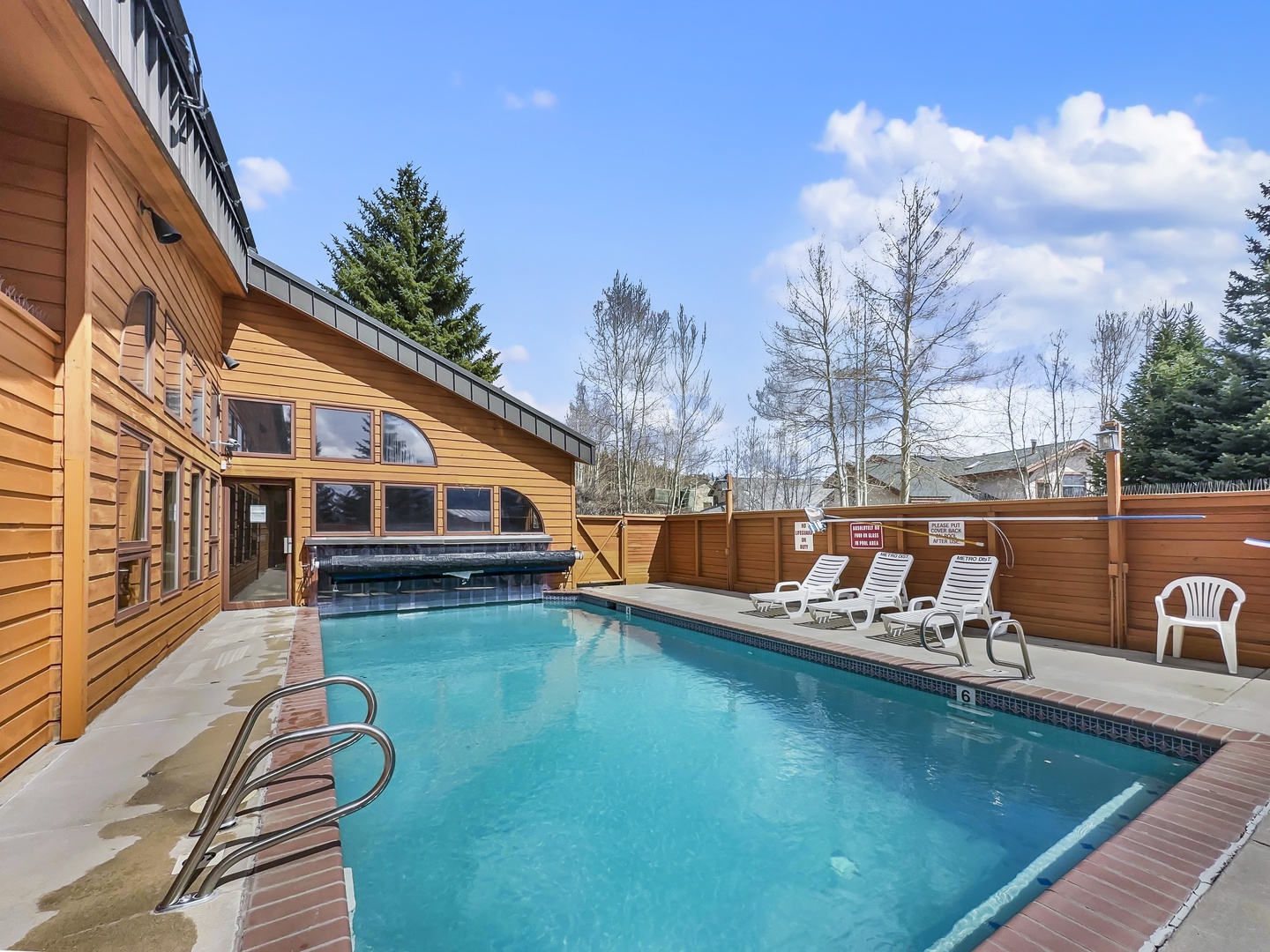 Sparkling pool awaits your afternoon swim, surrounded by warm wood privacy fencing and comfortable lounge chairs for soaking up the sun.