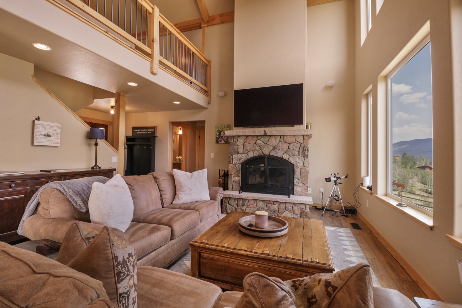 Unwind in your cozy living room with soaring ceilings, a stone fireplace, and stunning mountain views through expansive windows. Perfect for relaxing after a day of adventure.