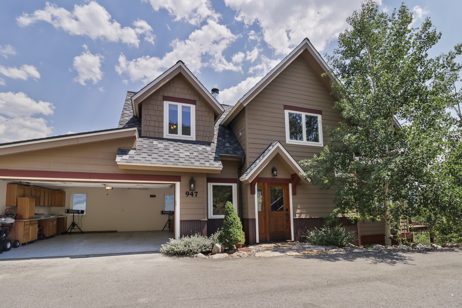A charming mountain retreat awaits you with its inviting wood facade, pitched rooflines, and spacious garage—nestled in a peaceful, tree-lined setting perfect for your getaway.