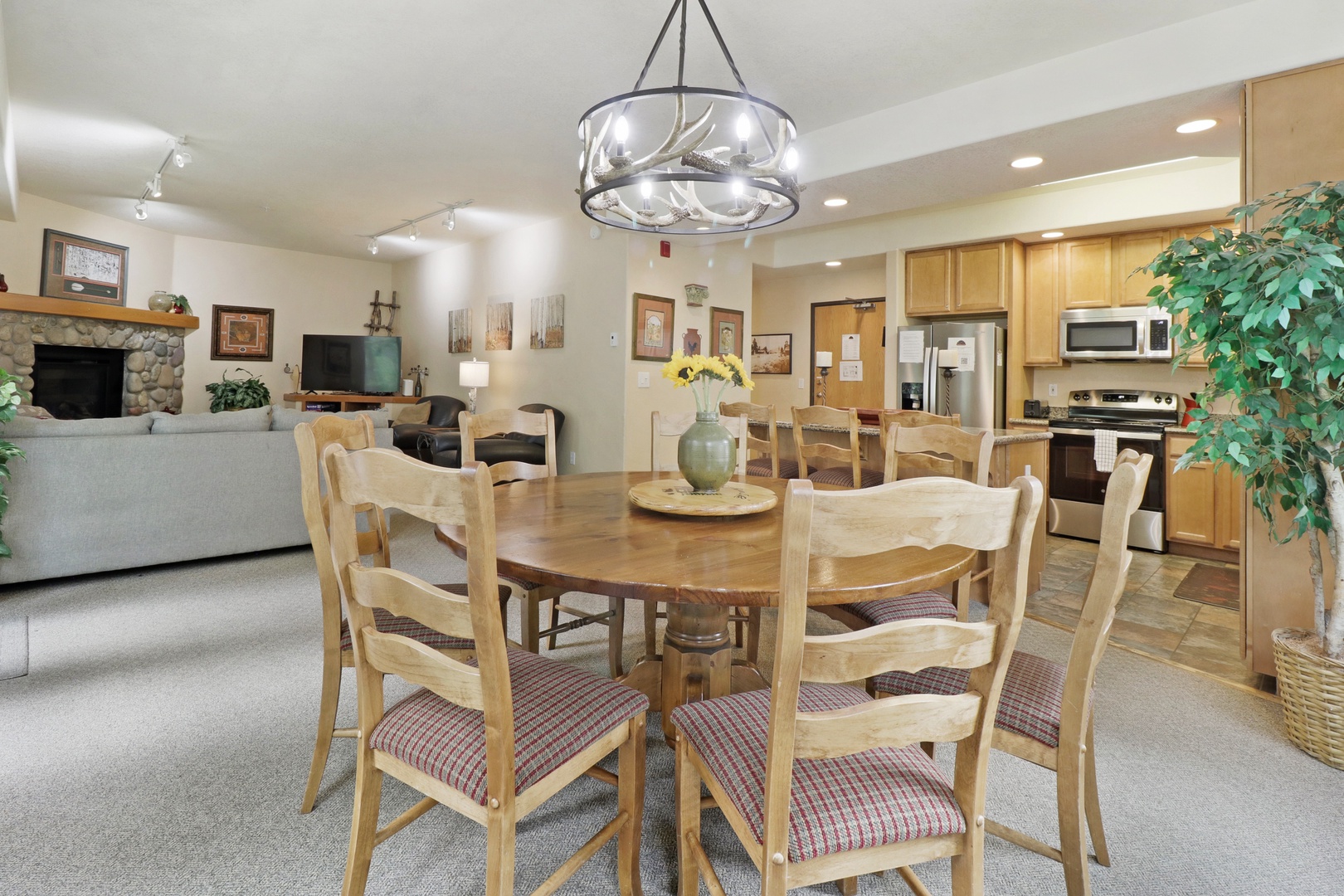Gather around the rustic chandelier and spacious dining table to share meals and stories. The open layout flows into a cozy living area with a stone fireplace and fully equipped kitchen—perfect for your mountain getaway.