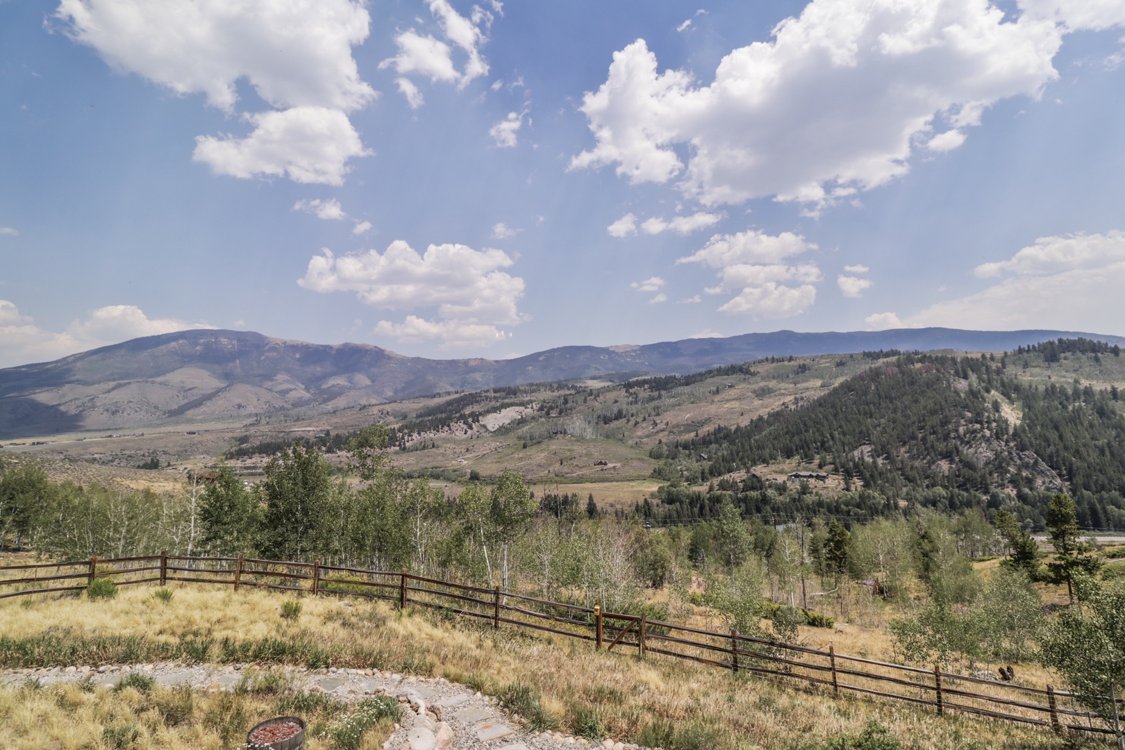 This property sits nestled among rolling hills and evergreen forests, offering a peaceful mountain setting with wide-open western vistas under vast skies.