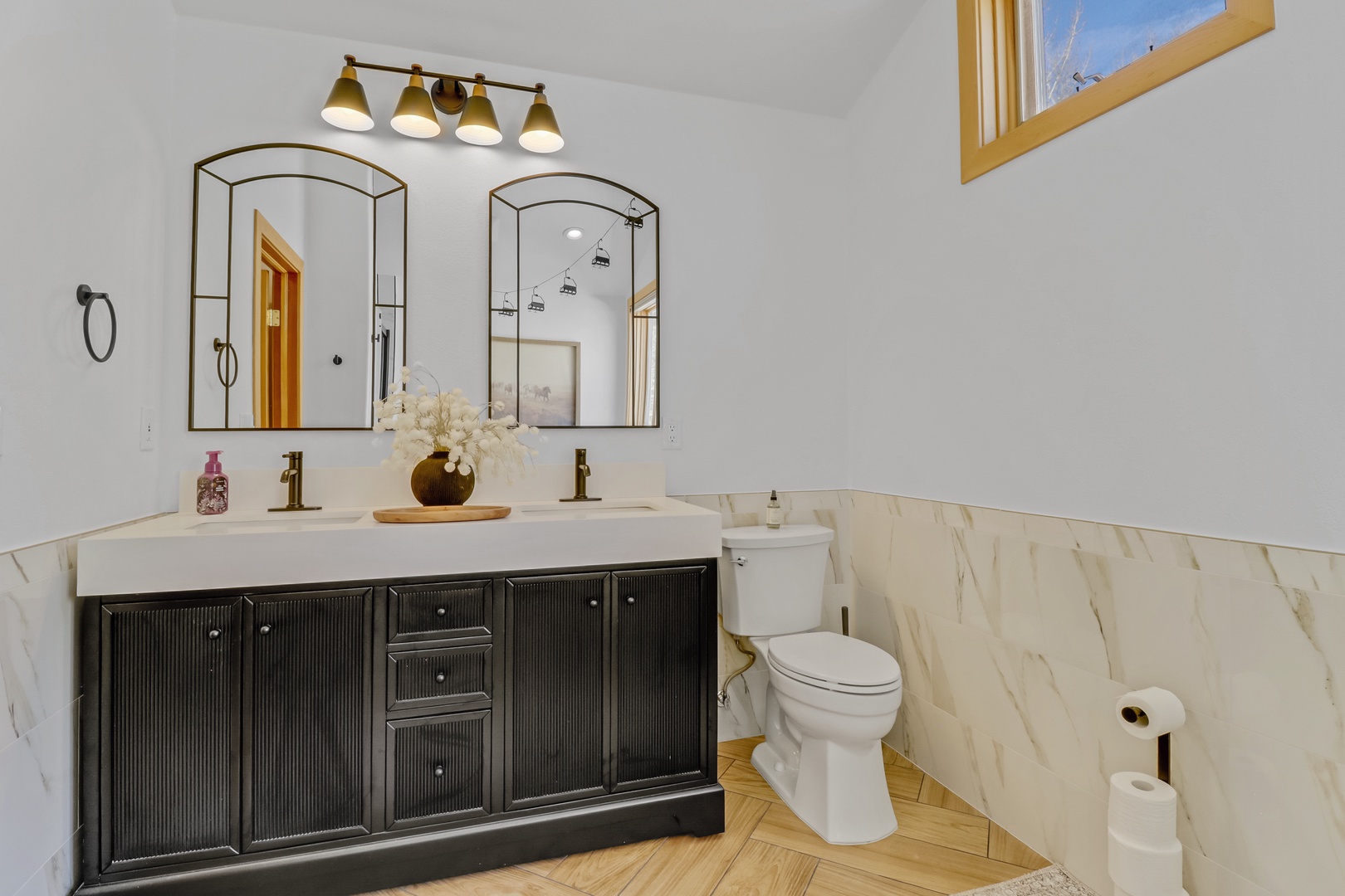 Step into your elegant bathroom featuring marble wainscoting, dual vanity sinks, and stylish fixtures that blend modern comfort with timeless design.