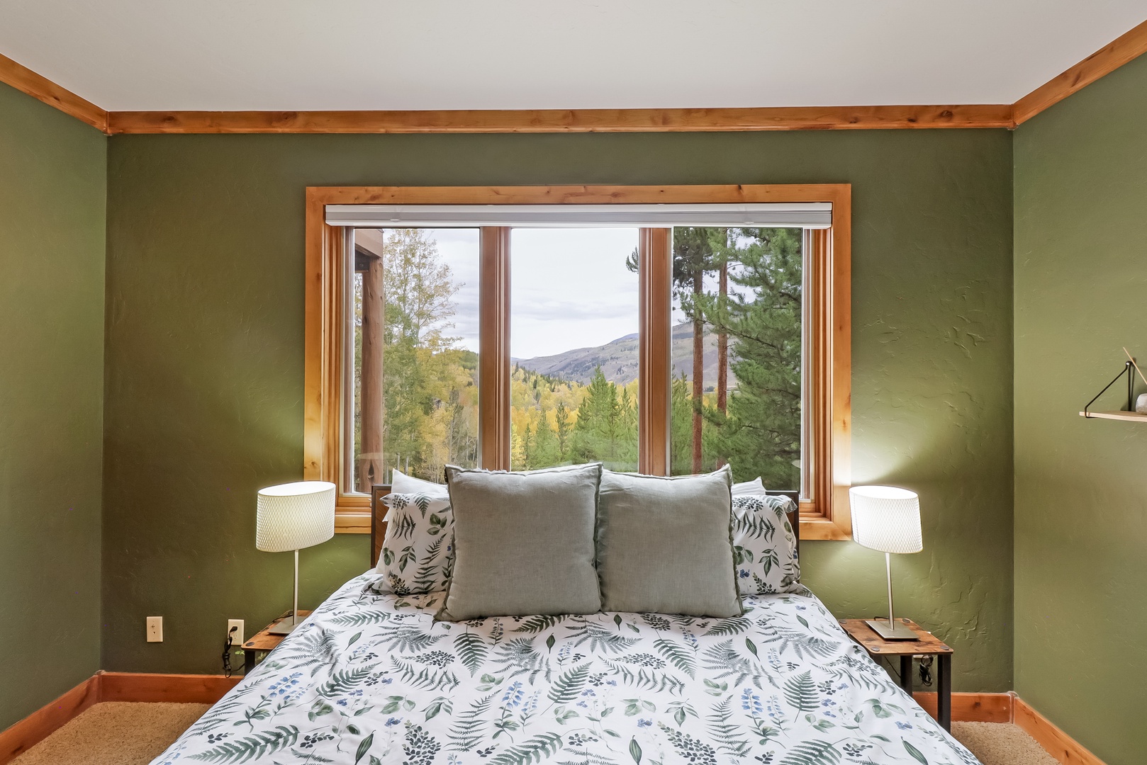 Wake up to mountain views framed by pines and autumn foliage. Your cozy retreat features natural wood accents and sage-green walls that bring the outdoors in.