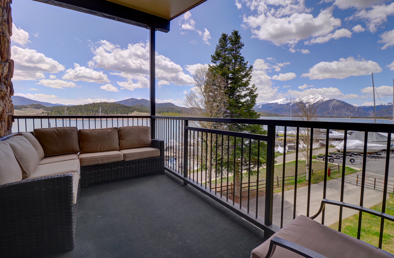 Stunning lake and mountain views await from this inviting covered balcony, where you can unwind on plush seating while taking in the natural beauty surrounding you.