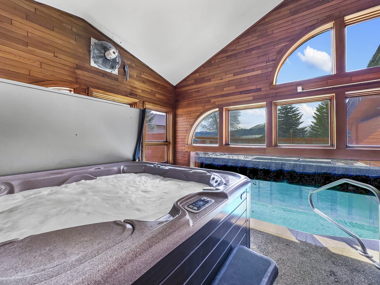Unwind in shared spa sanctuary with bubbling hot tub and refreshing pool, surrounded by warm wood and mountain views.