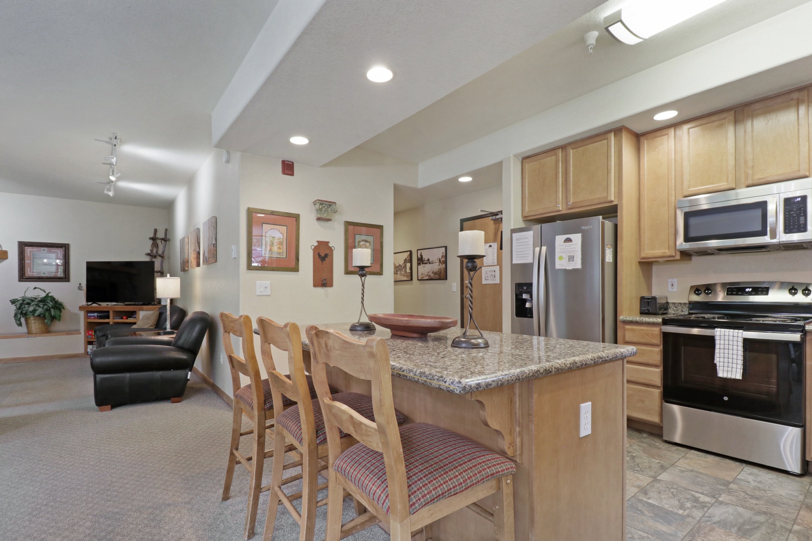 Step into this bright, open-concept space where your vacation comes together. A fully equipped kitchen with granite counters and stainless appliances flows seamlessly into your cozy living area—perfect for gathering after a day of adventure.